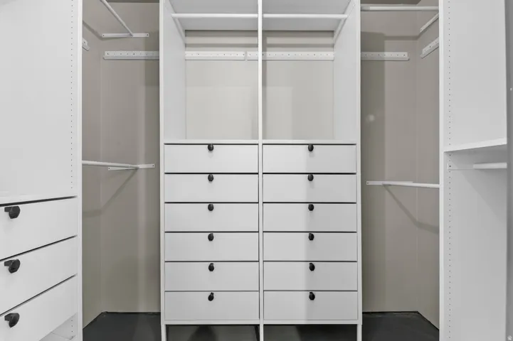 Custom closet system featuring multiple integrated drawer units with matte black hardware, adjustable shelving, and hanging rods