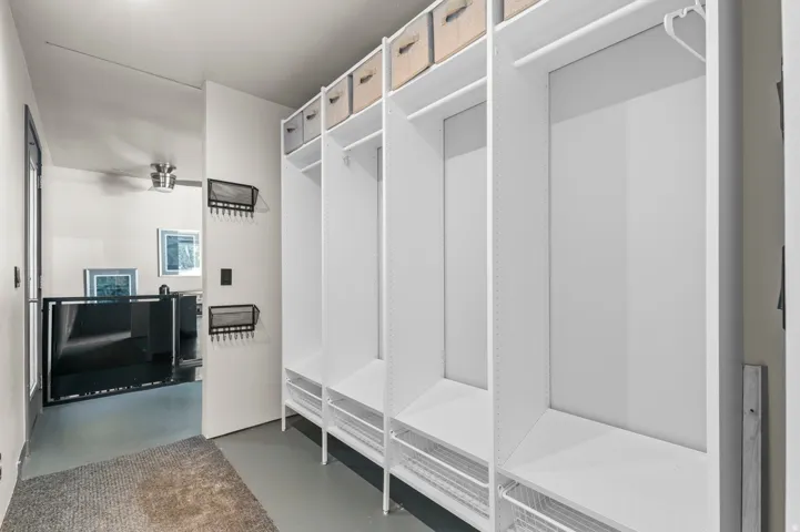 Built-in white storage system featuring multiple compartments, hanging rods, and wire basket drawers