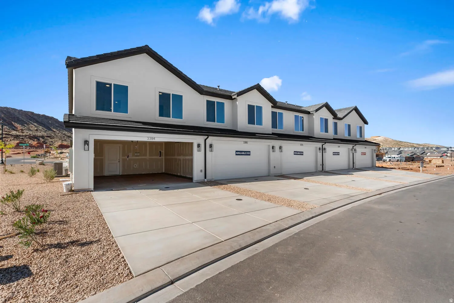 Contemporary townhome row featuring white stucco exteriors with dark trim and pitched roofs