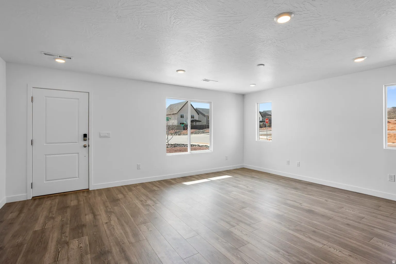 Spacious room featuring wood-finish flooring, recessed lighting, and multiple windows