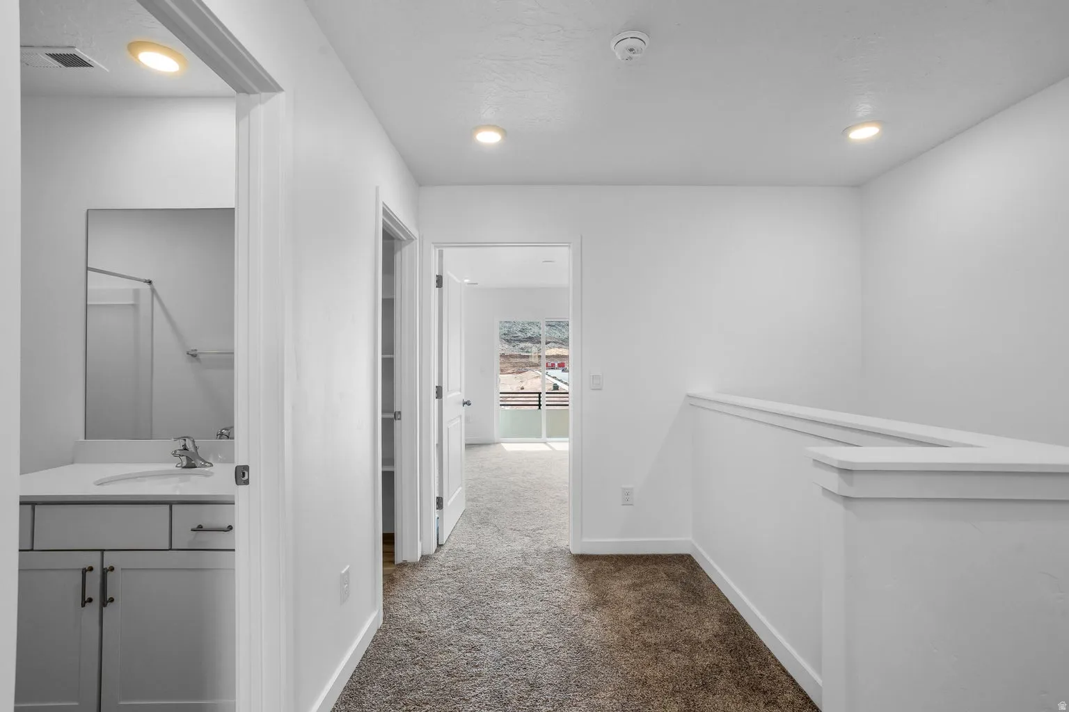 Upper-level landing featuring recessed lighting, a neutral carpet, and white balustrade
