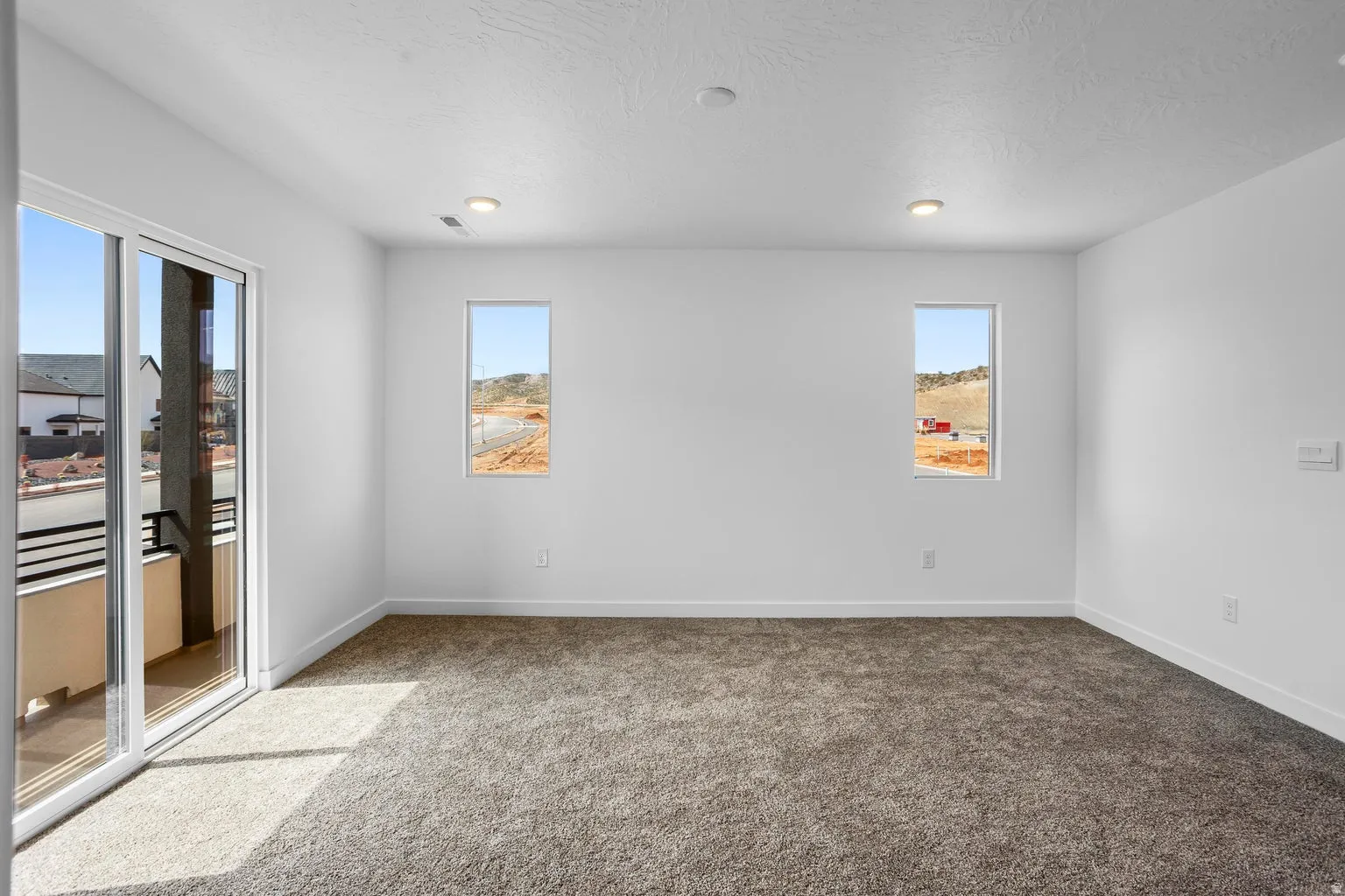 Spacious room featuring neutral carpet flooring and white walls