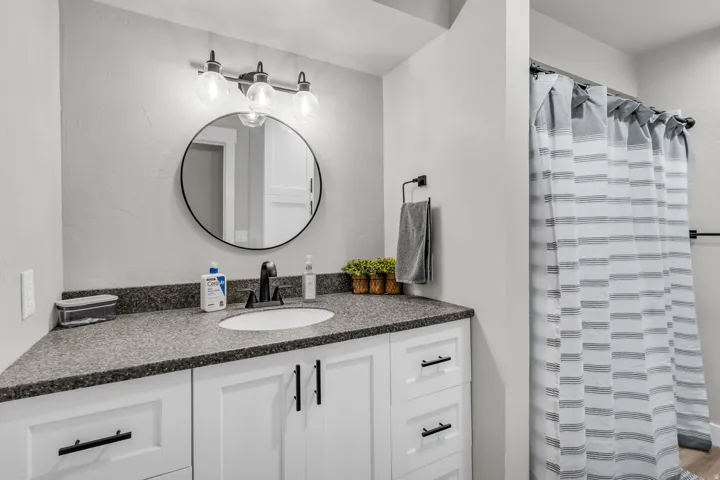 Bathroom vanity featuring a dark speckled countertop with an undermount sink and matte black faucet