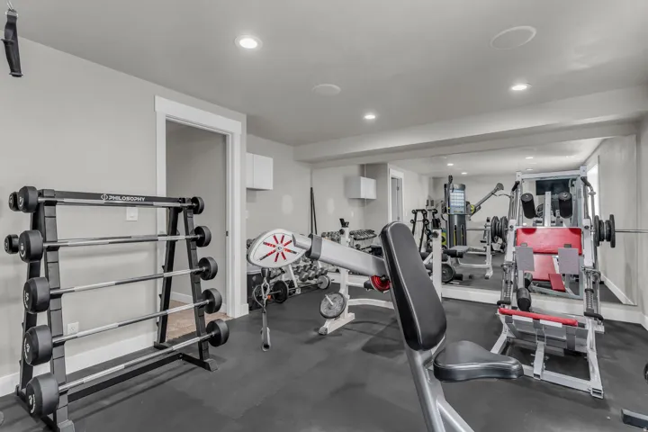 Dedicated fitness area featuring rubber flooring, recessed lighting, and a full-wall mirror