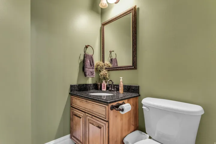 Bathroom vanity with a dark speckled countertop, an undermount sink, and a bronze-finish faucet