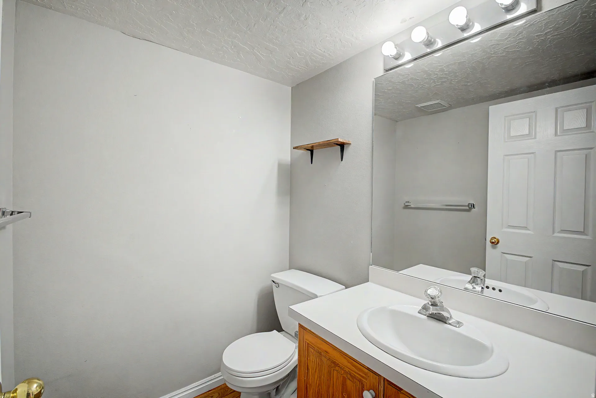 Bathroom featuring a white vanity with an integrated sink, chrome faucet, and wood-finish cabinetry