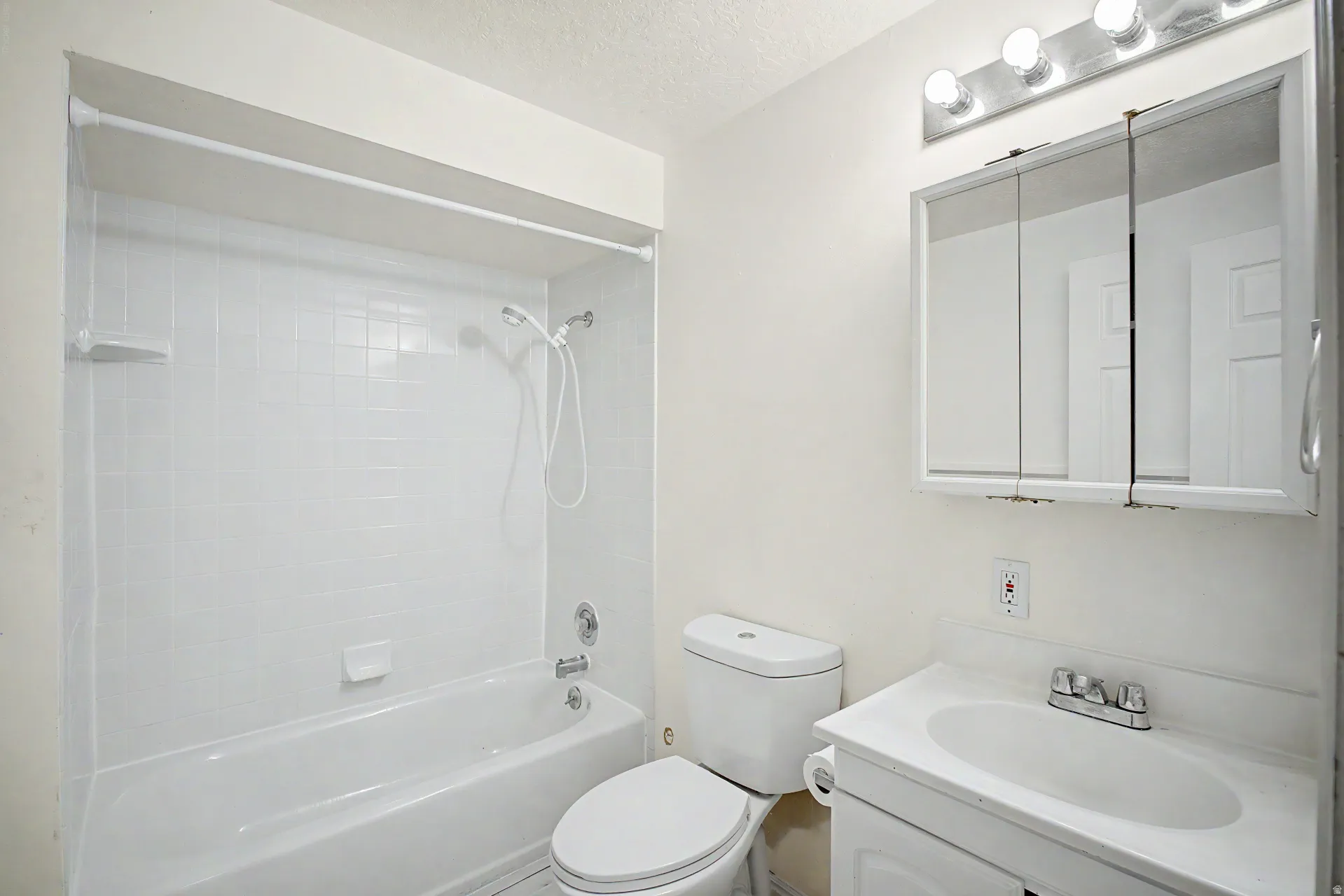 Bathroom featuring a white bathtub with subway tile surround, a white toilet, and a vanity with an integrated sink