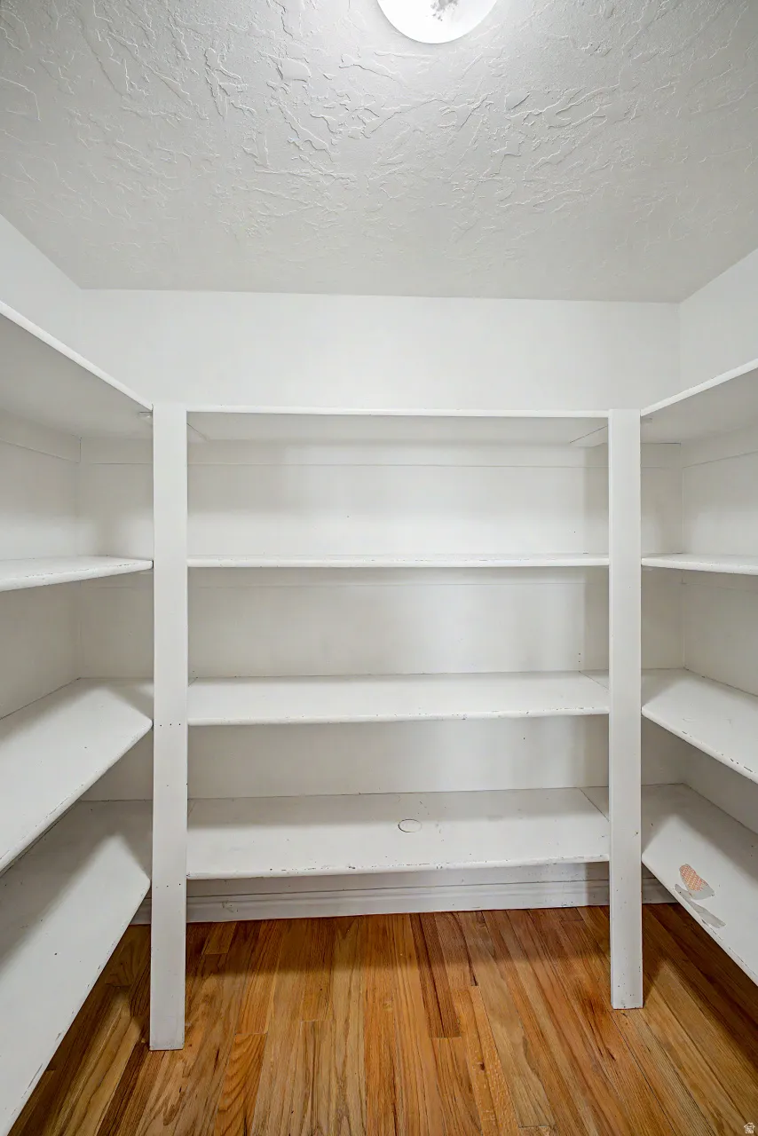 U-shaped shelving system featuring multiple shelves, white painted finish, wood-finish flooring, and a ceiling-mounted light fixture