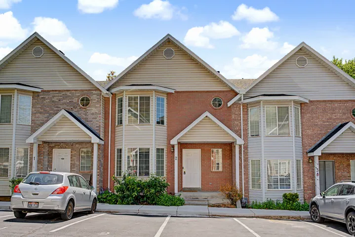 Multi-story townhome exterior featuring red brick and light-toned siding