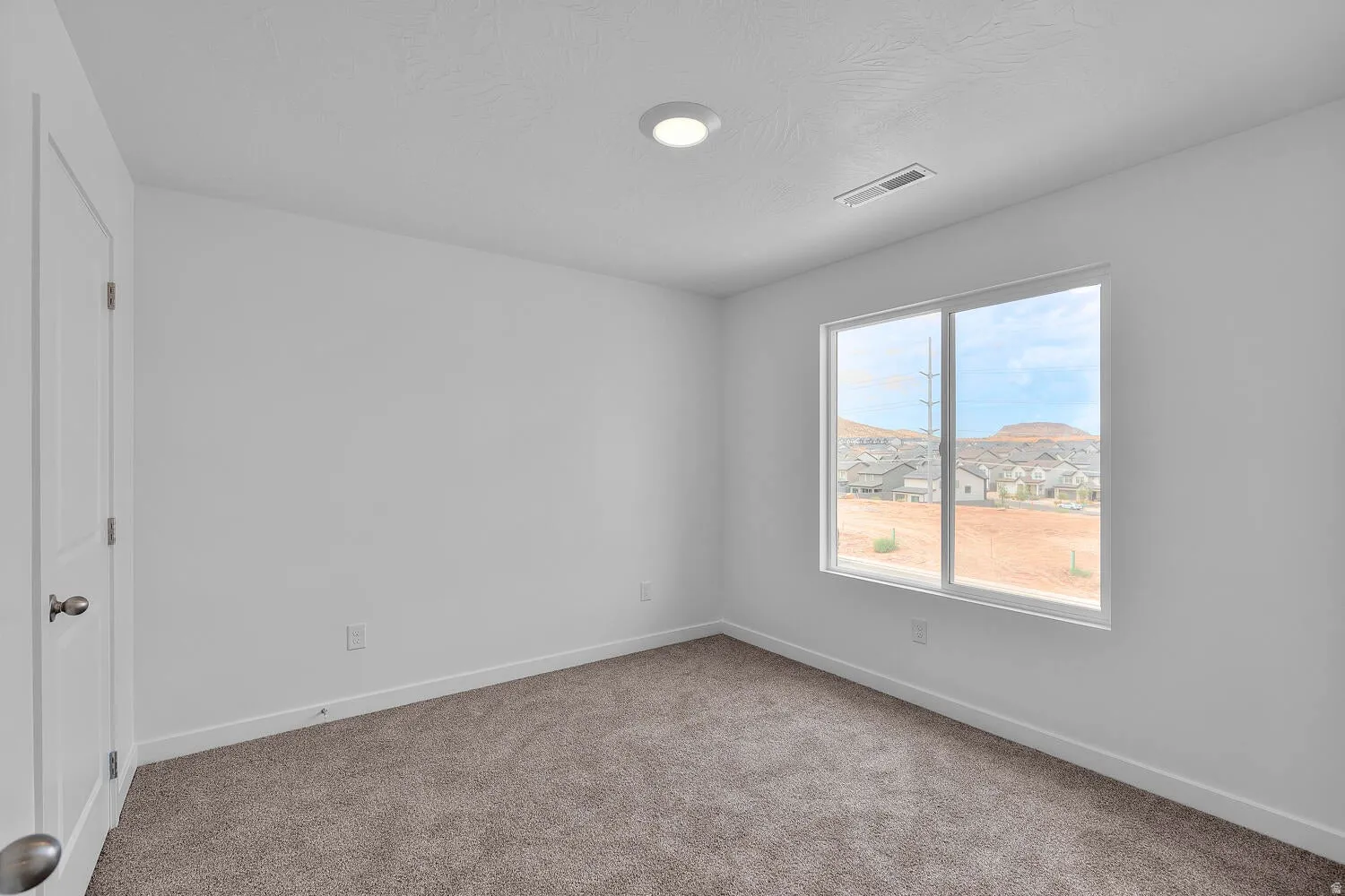 Bright room featuring a large window, neutral carpeting, white walls, and a recessed ceiling light