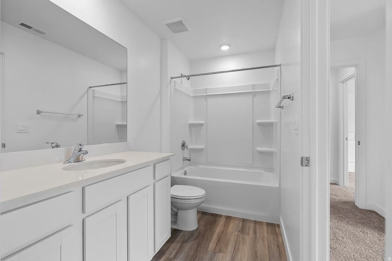 Bathroom featuring a single vanity with a white countertop and integrated sink, chrome faucet, and white cabinetry