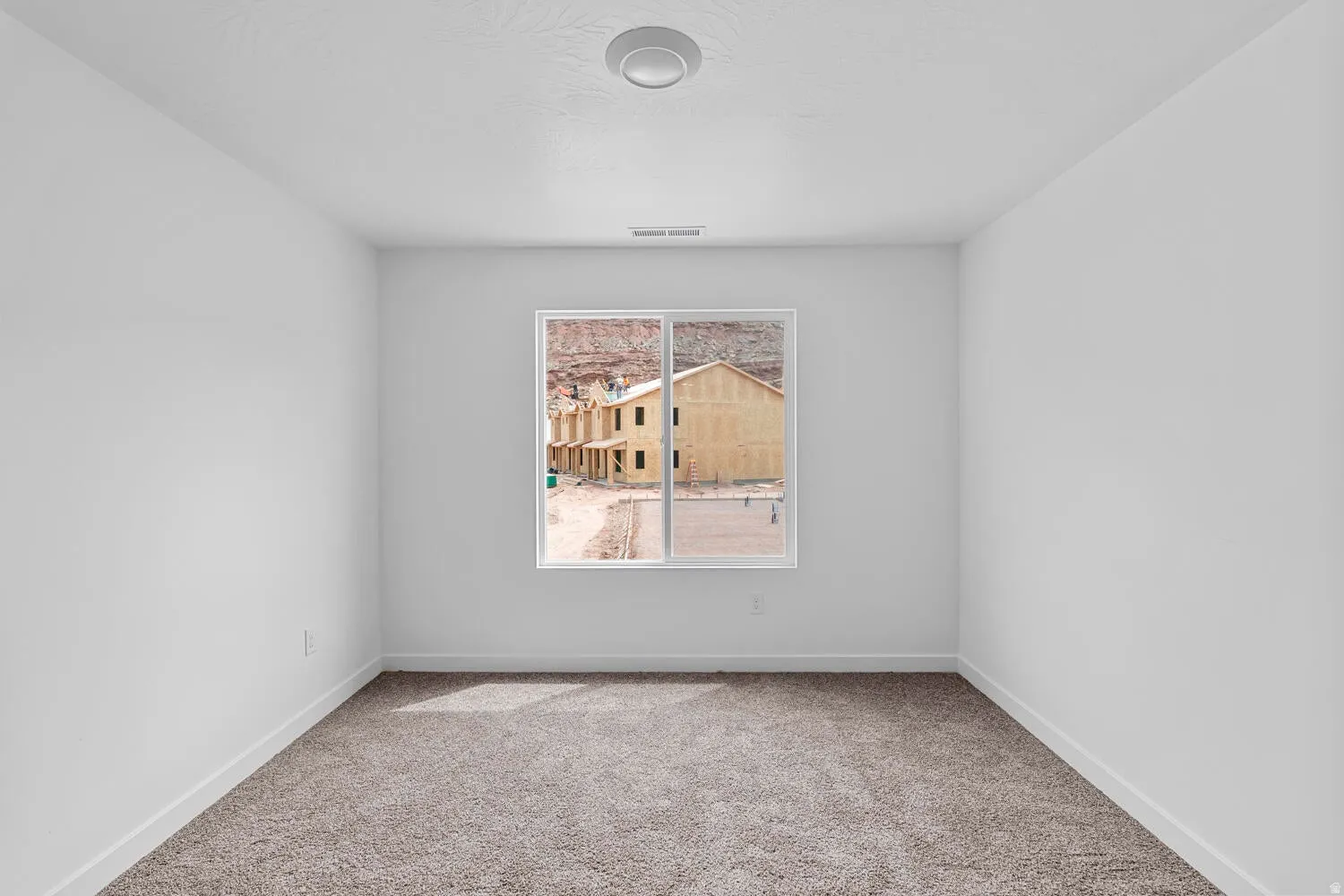 Spacious room with plush carpeting, crisp white walls, and a recessed ceiling light