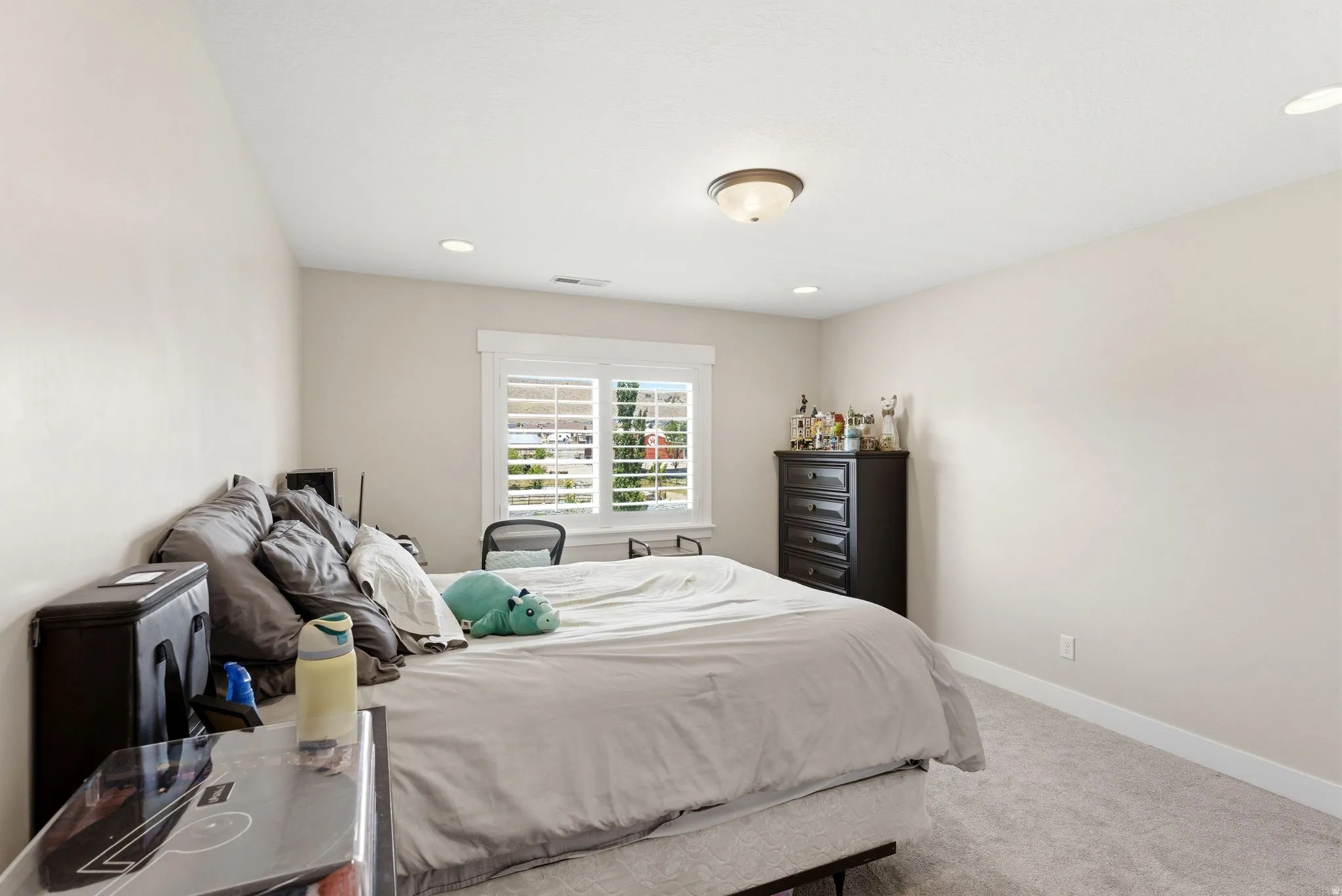 Bedroom featuring a window with white louvered shutters, recessed lighting, a flush-mount ceiling fixture, and light-toned carpeting