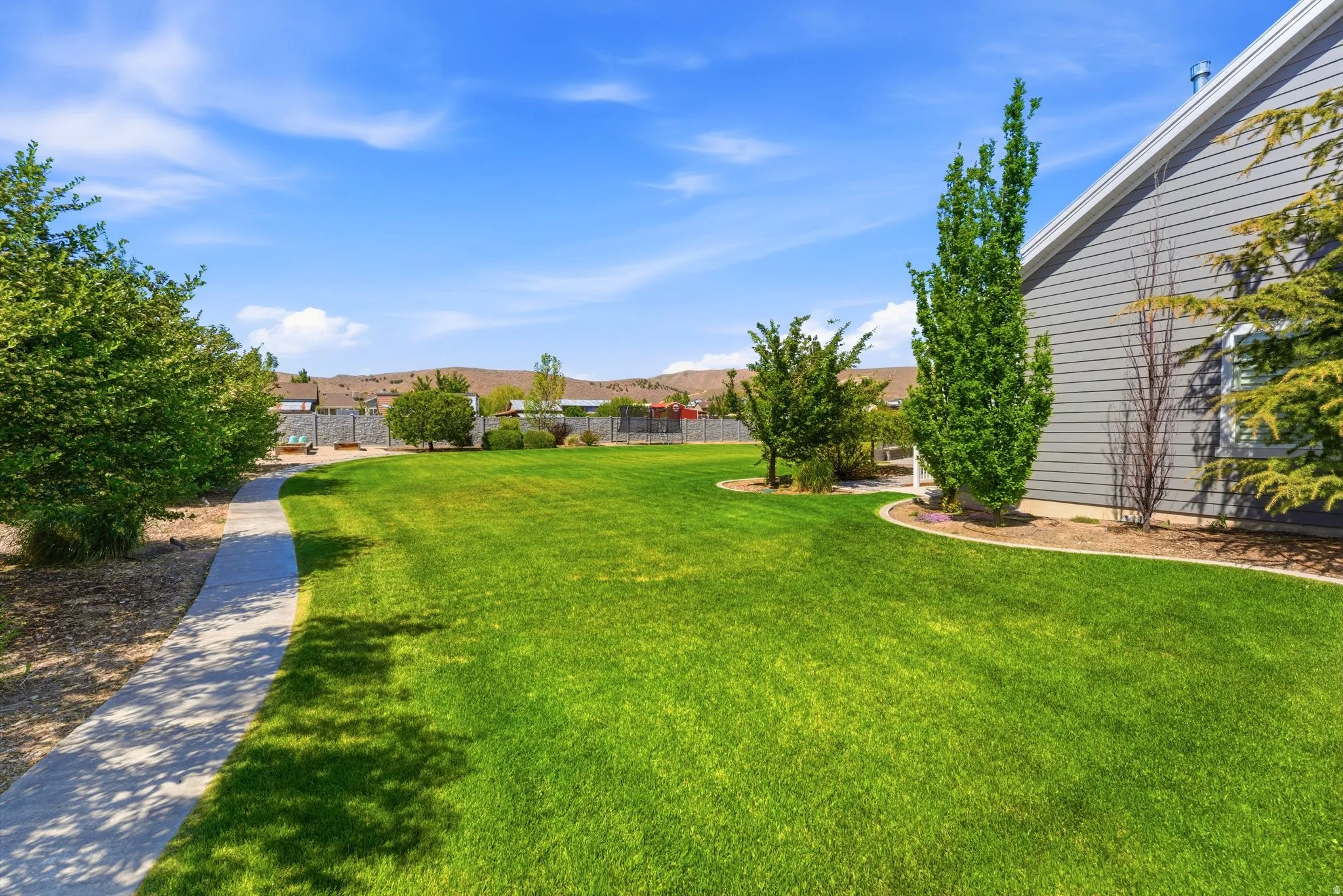 Expansive lawn area with mature trees and a concrete pathway