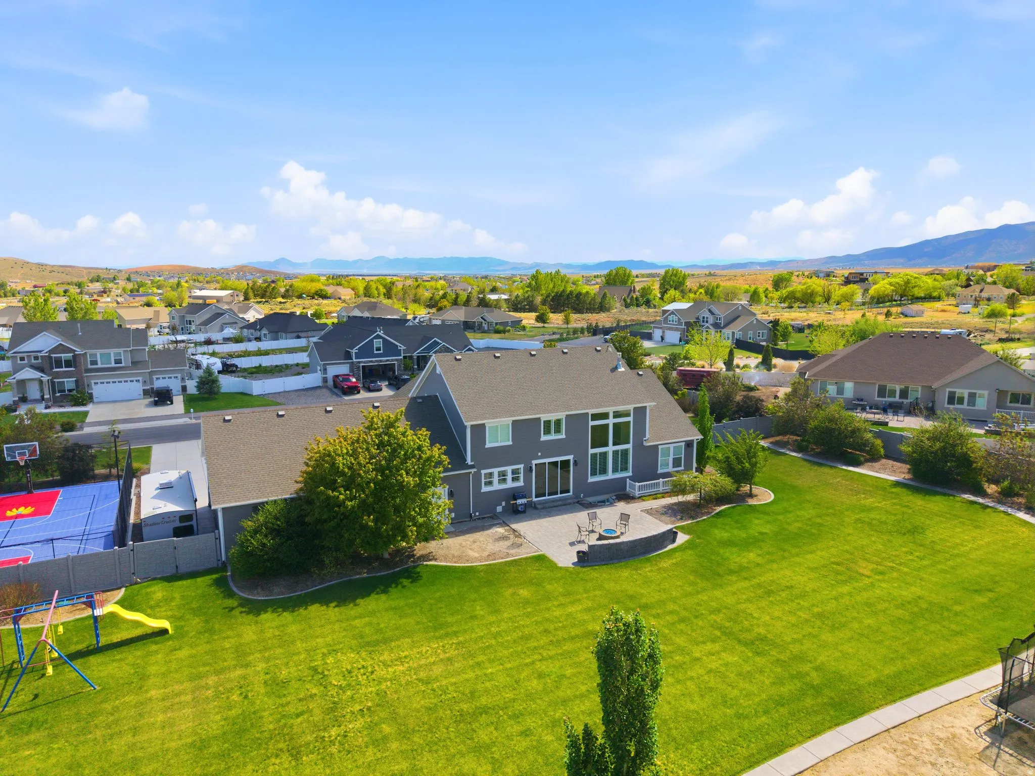 Expansive backyard featuring a manicured lawn, paved patio, and established trees