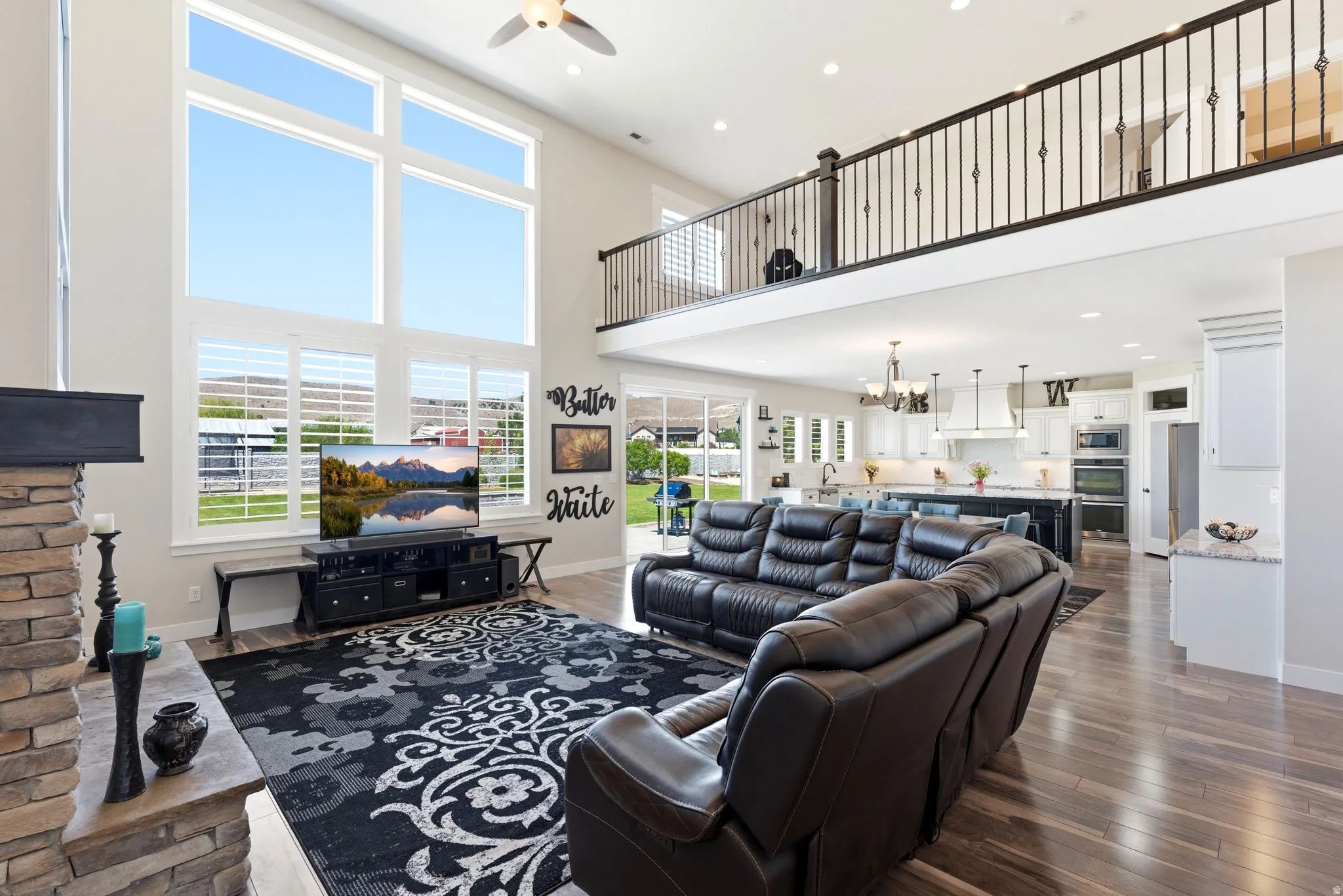 Two-story living area featuring extensive window treatments and wood-finish flooring
