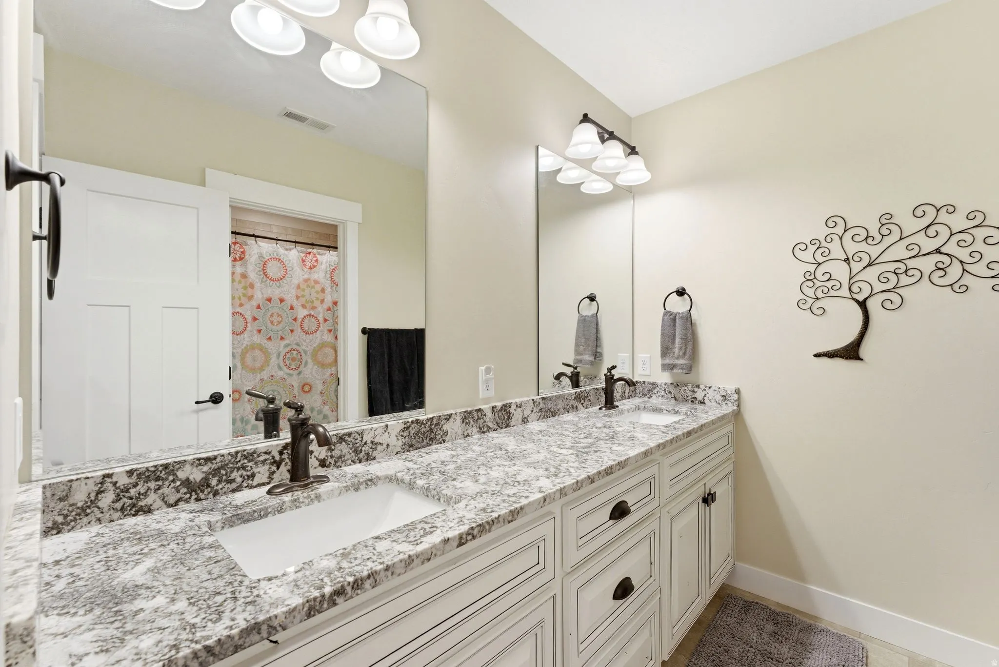 Dual vanity featuring white shaker-style cabinetry and granite countertops