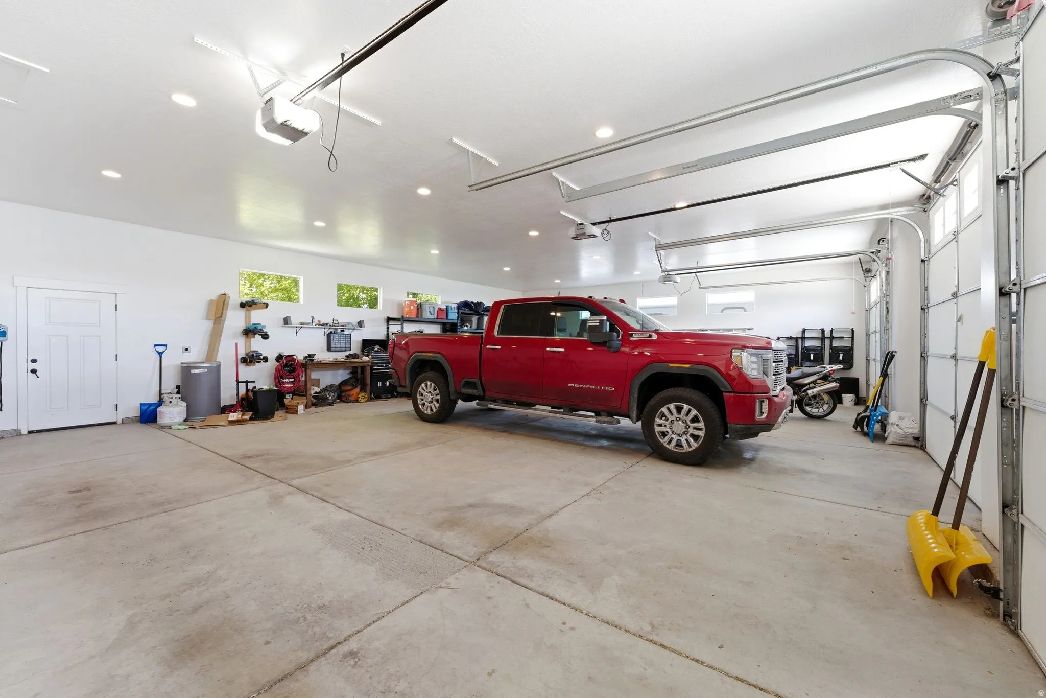 Spacious garage featuring concrete flooring, multiple overhead garage doors, recessed ceiling lighting, and transom windows