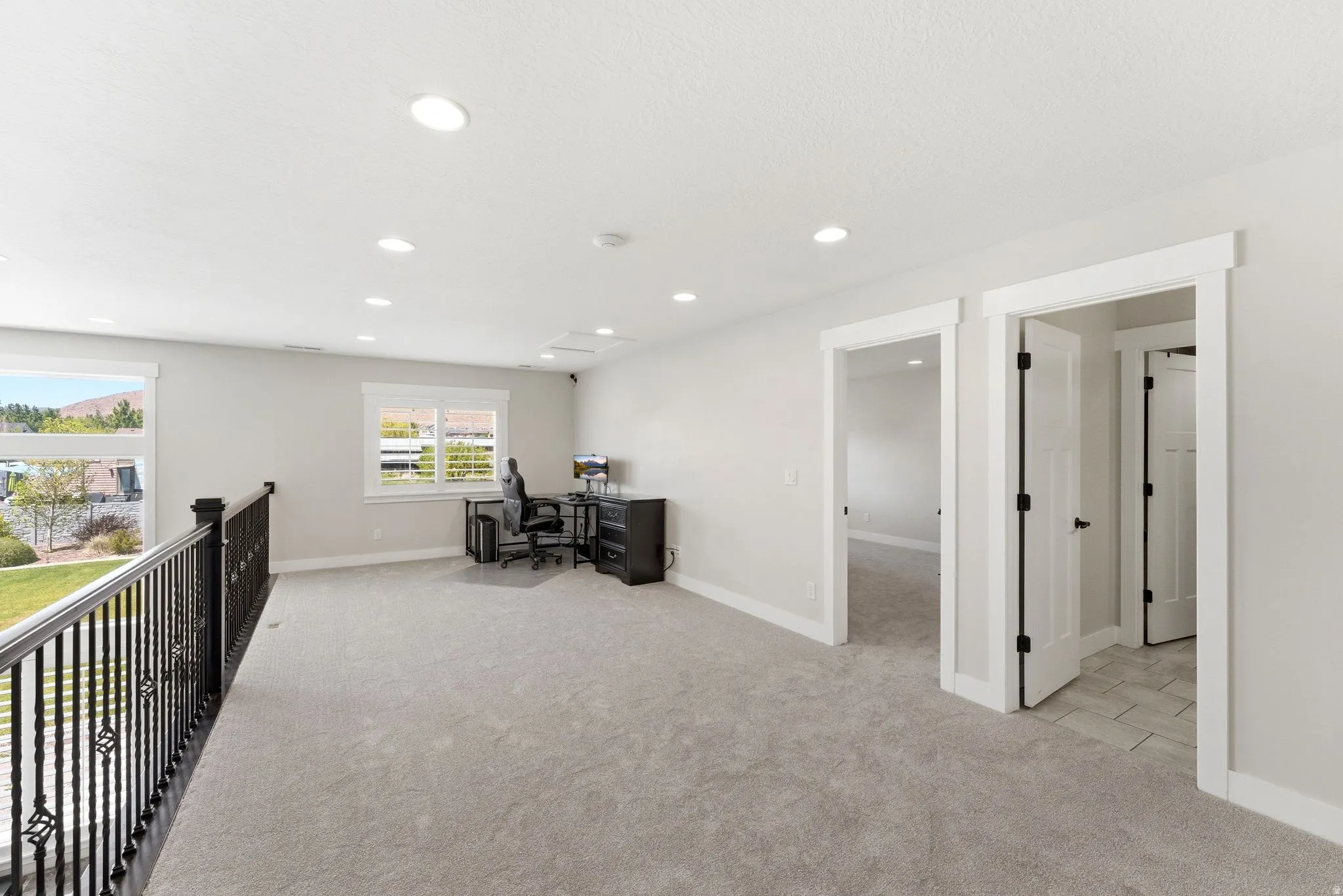 Expansive carpeted loft space with recessed lighting and multiple windows