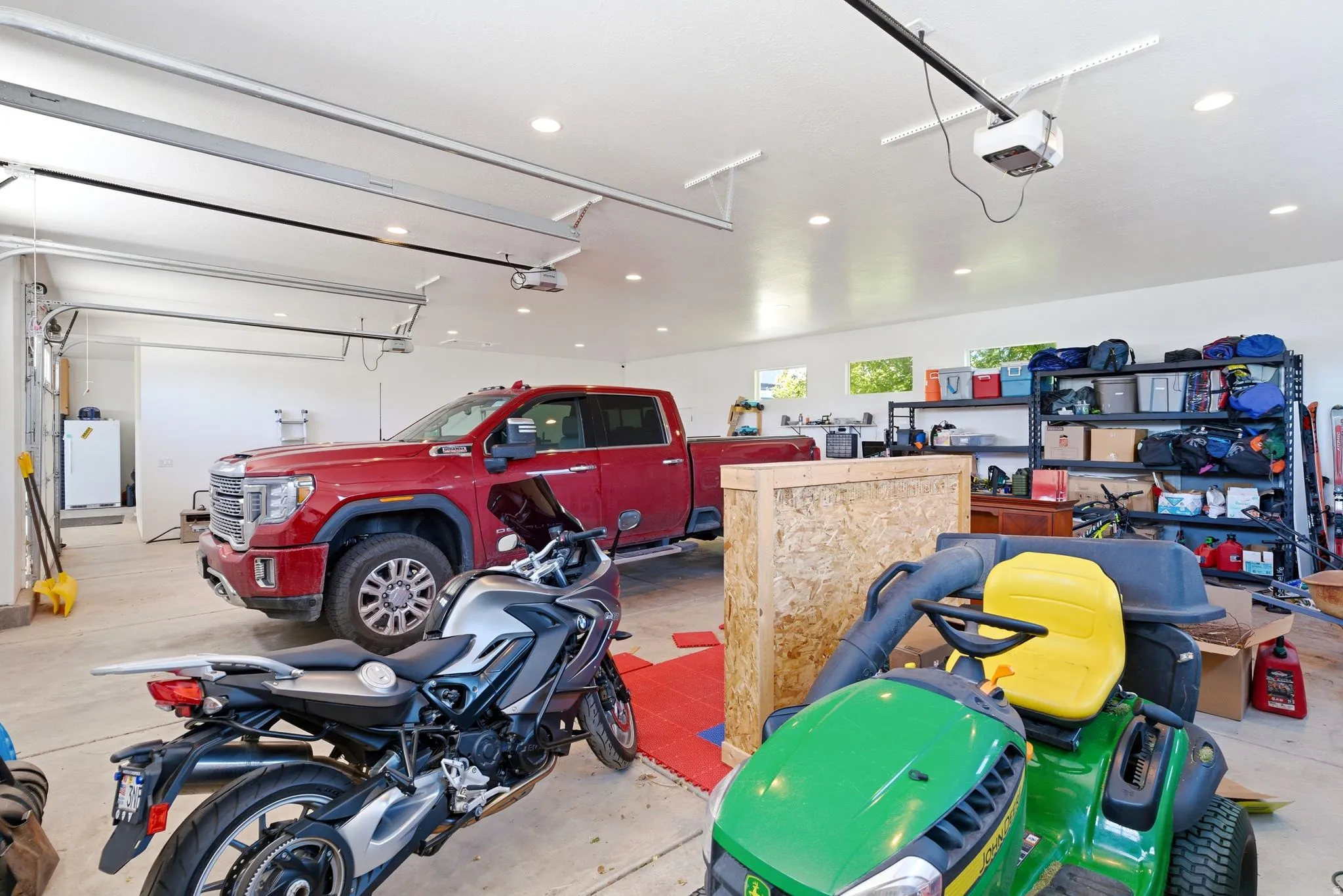 Spacious garage featuring high ceilings, multiple garage door openers, recessed lighting, concrete flooring, and built-in shelving