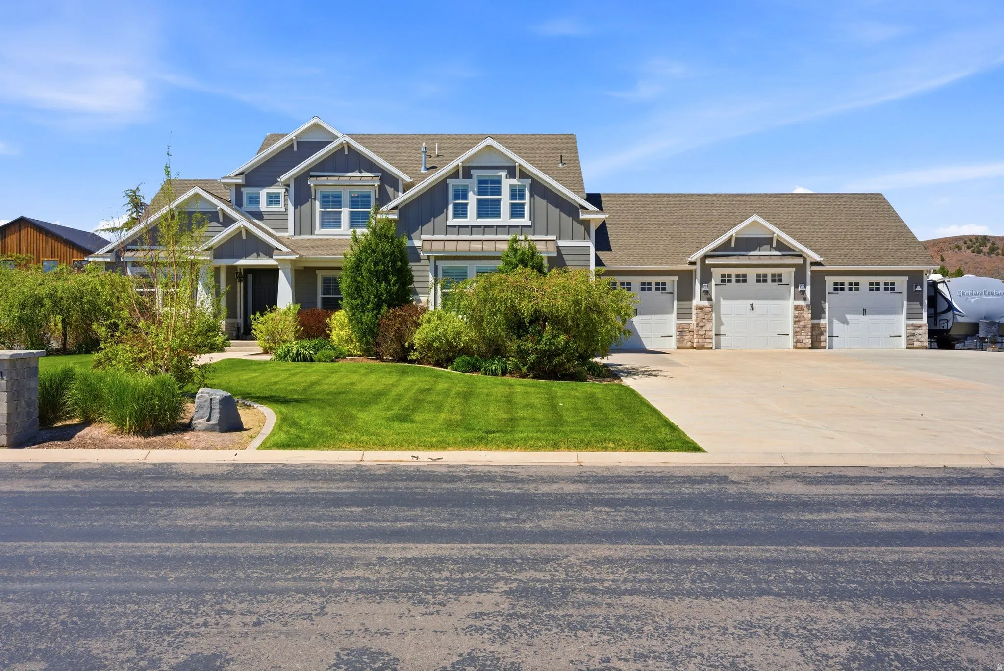 Contemporary gray two-story residence featuring white trim, a multi-car garage, and a lush, manicured lawn