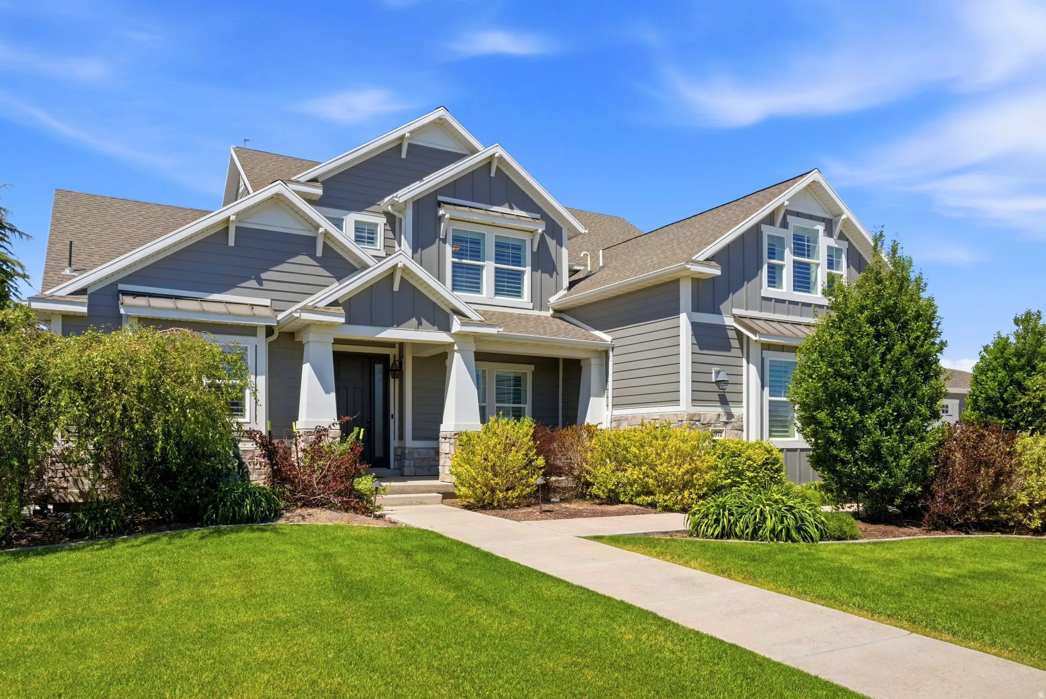 Contemporary residence featuring a prominent gabled roofline, gray siding, and white trim