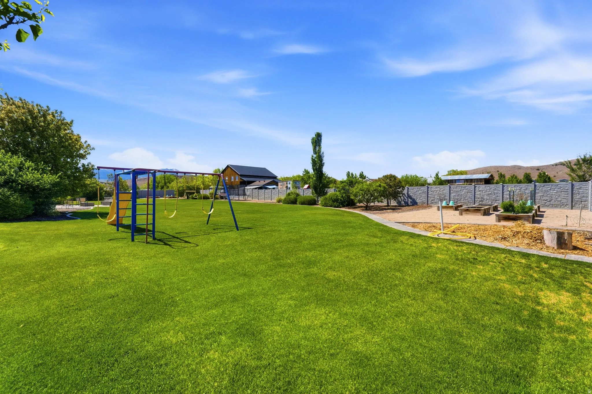 Expansive grassy yard with a blue and yellow playset