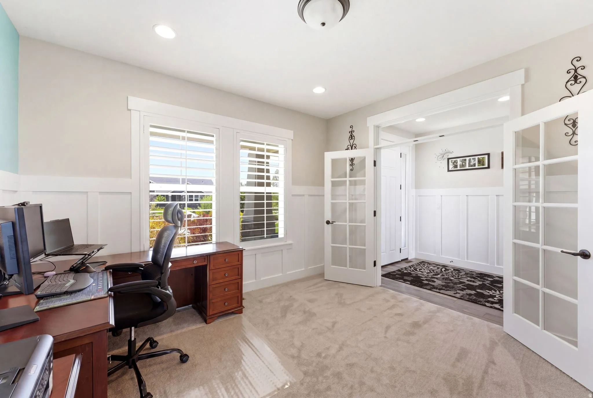 Room featuring a light tan carpet, white board and batten wainscoting, and recessed lighting
