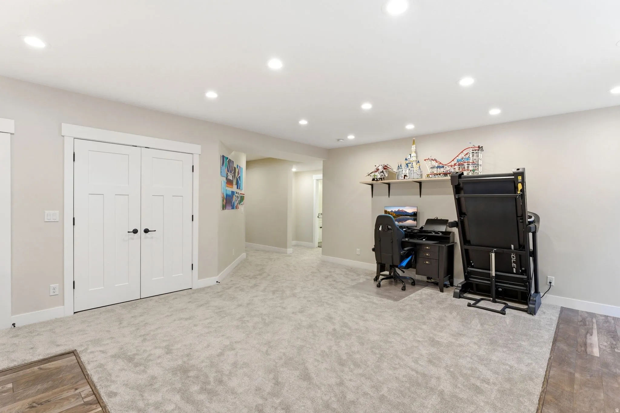 Spacious room featuring plush carpeting, recessed lighting, white trim, and a built-in wall shelf