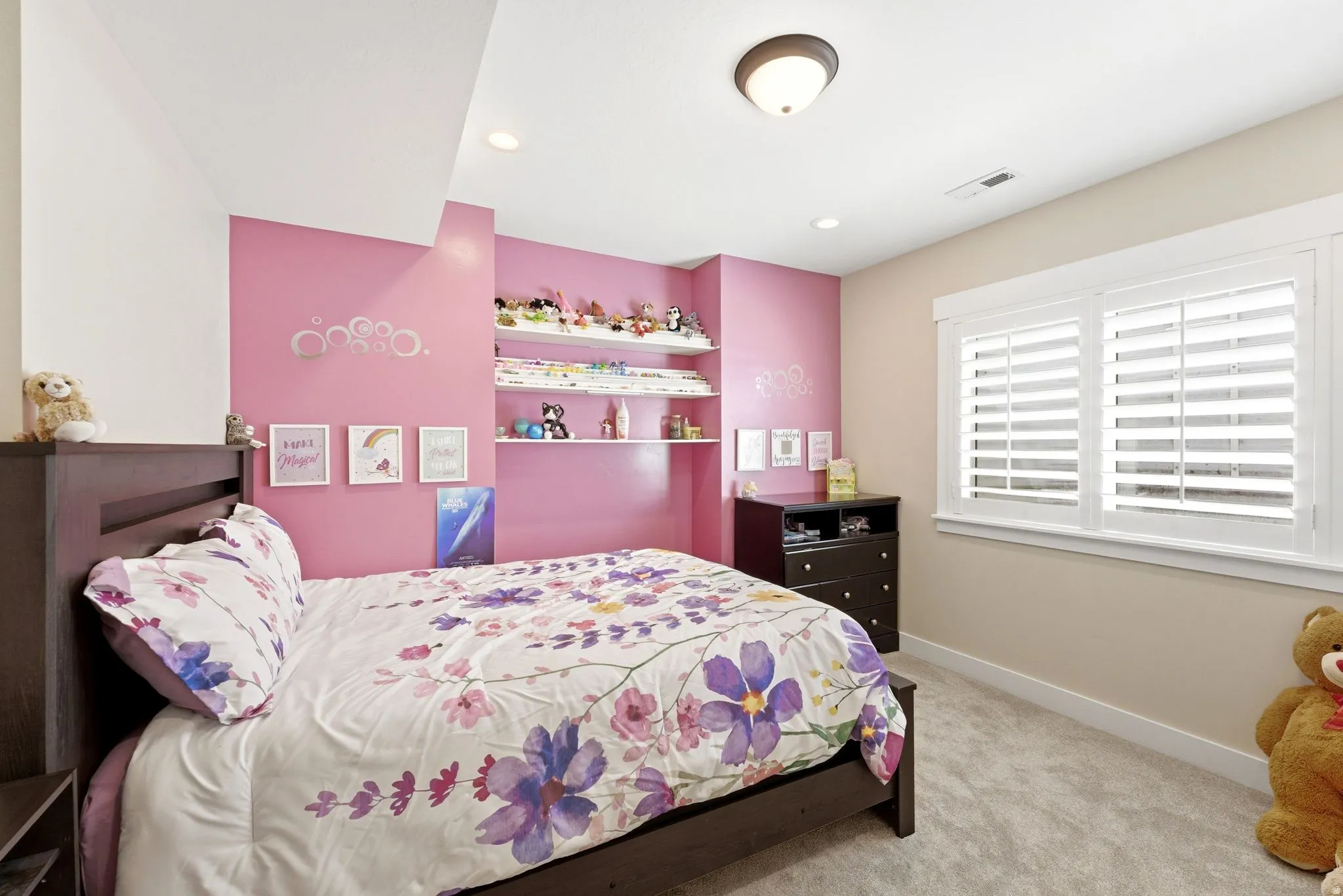 Bedroom featuring a built-in wall niche with shelving, recessed lighting, and a window with white plantation shutters
