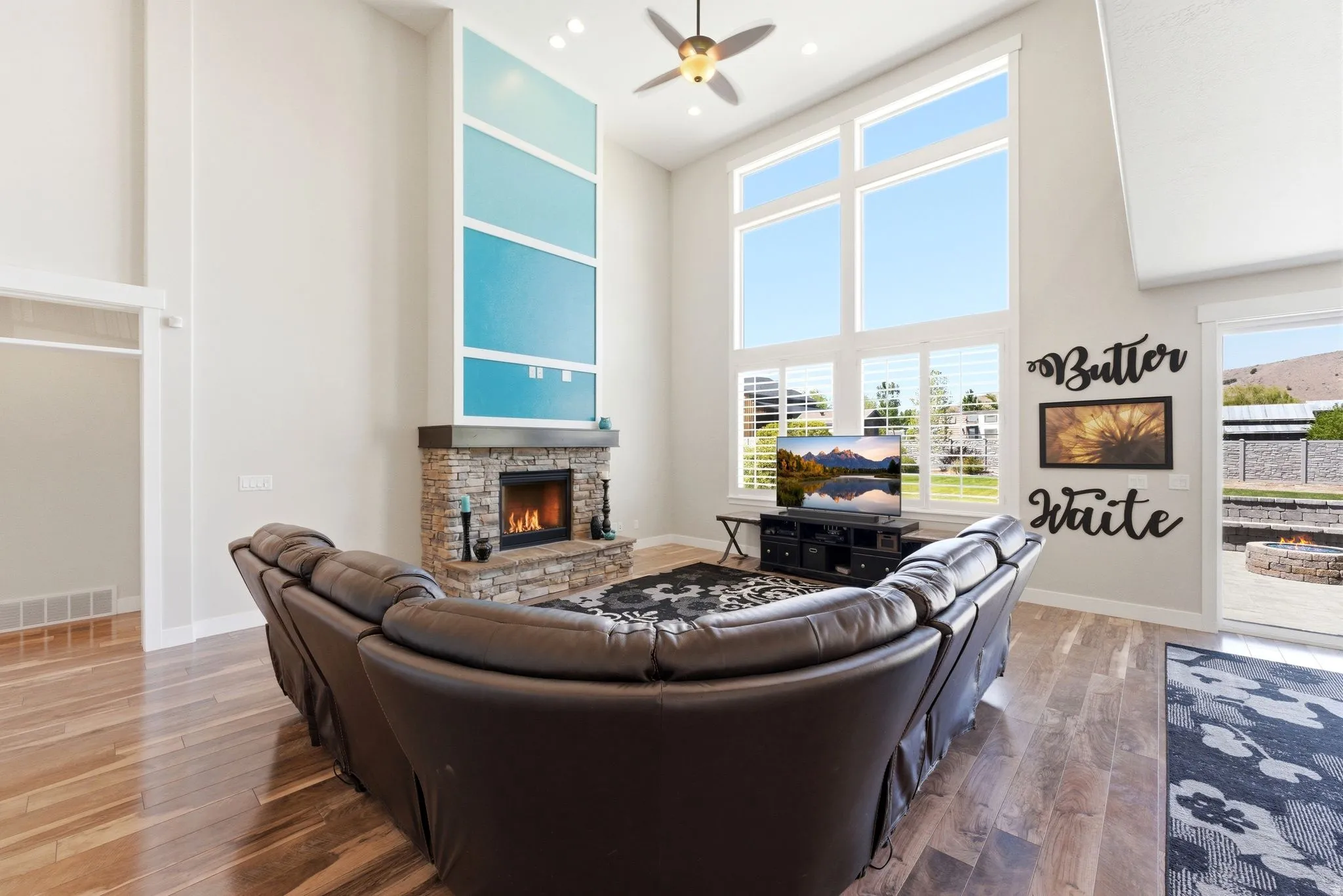 Two-story living area featuring wood-finish flooring, a stone-clad fireplace, and a striking floor-to-ceiling accent wall