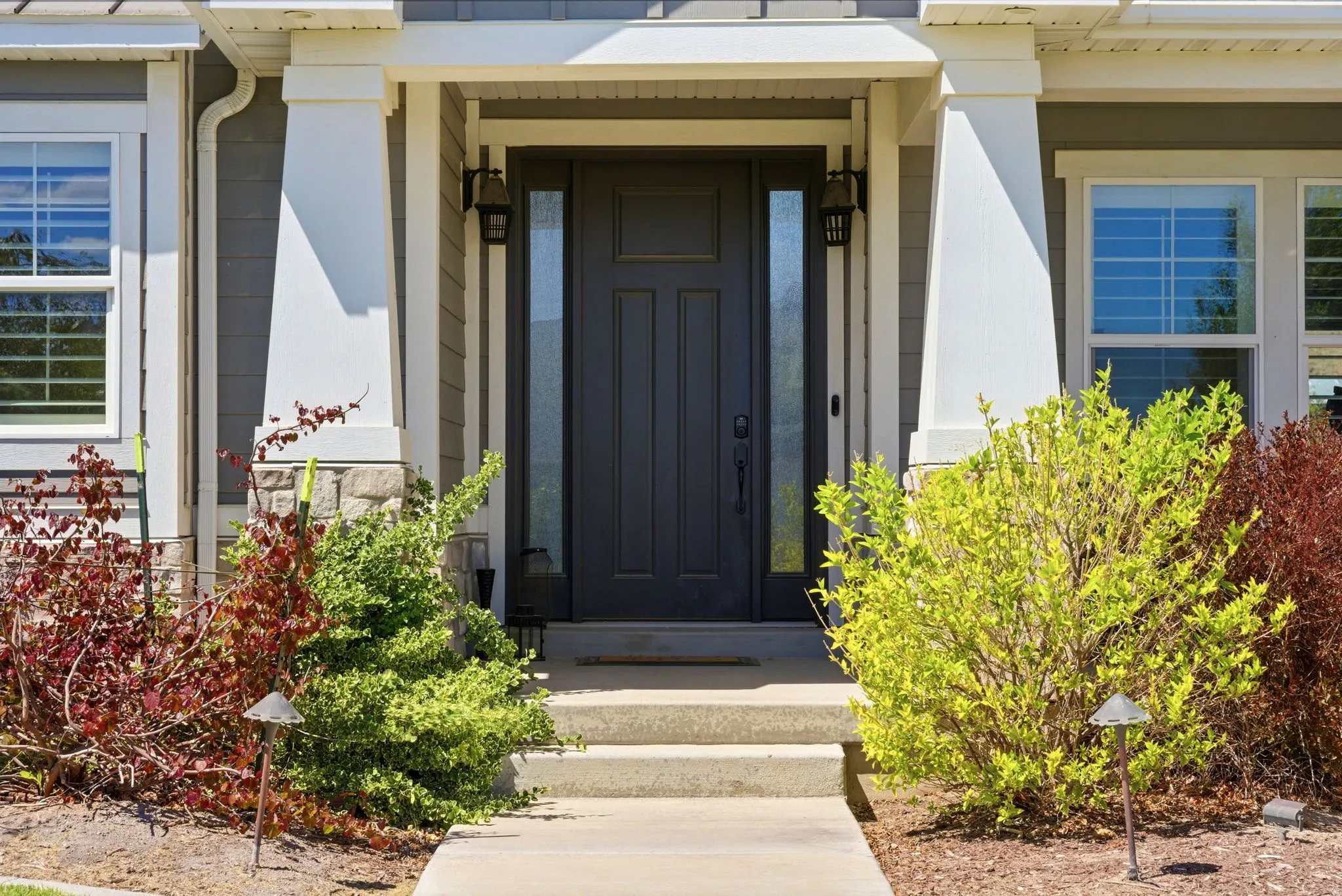 Entryway featuring a dark paneled door with side-light windows, complemented by a covered porch