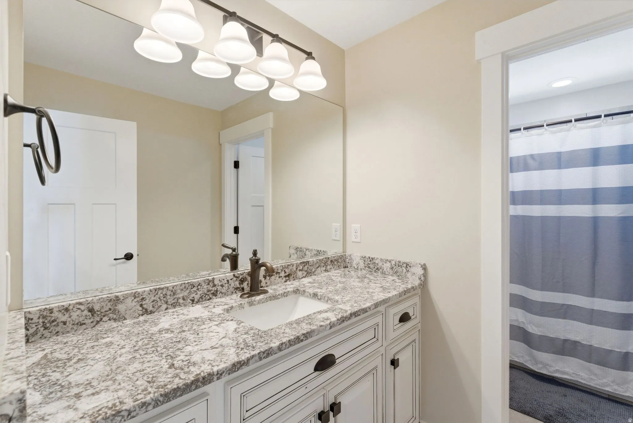 Bathroom vanity featuring a single basin sink and a speckled countertop