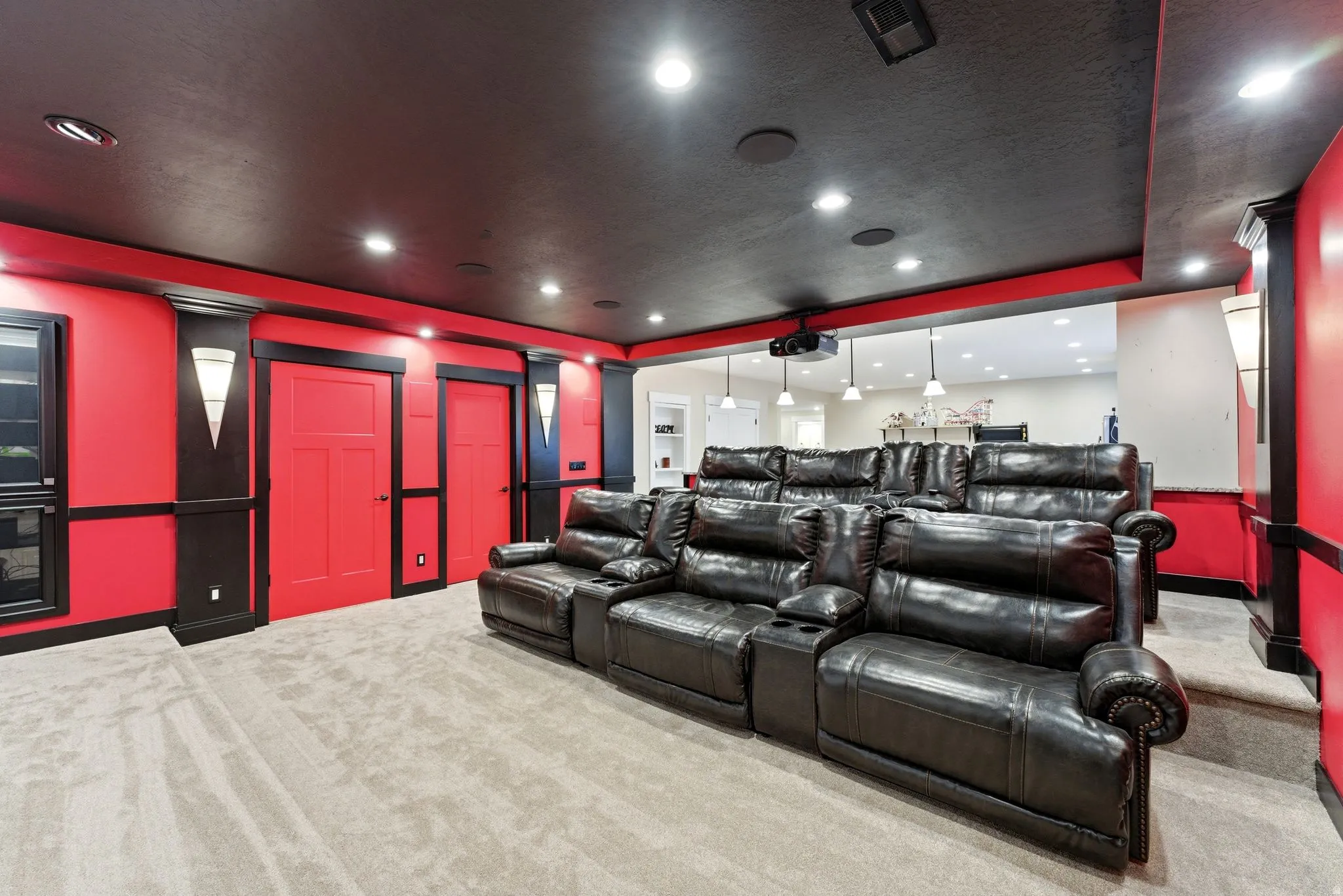 Dedicated media room featuring tiered seating, recessed ceiling lighting, and a mounted projector