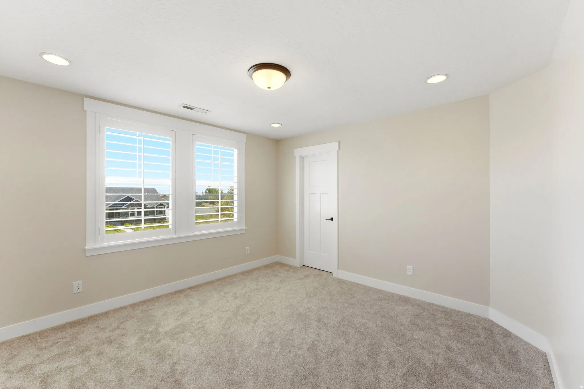 Neutral-toned room featuring a pair of windows with white plantation shutters, recessed lighting, and a flush mount ceiling fixture
