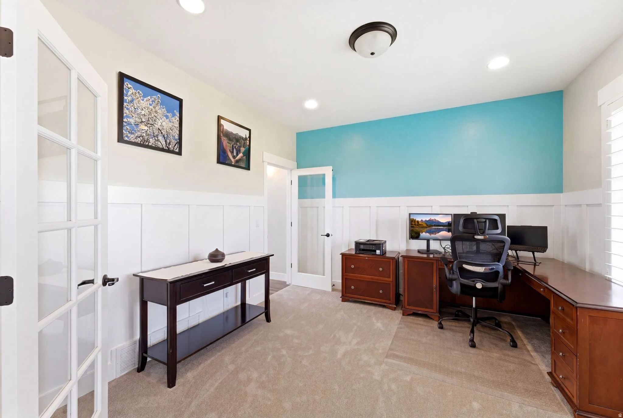 Office space with board and batten wainscoting, recessed ceiling lighting, and a bright accent wall
