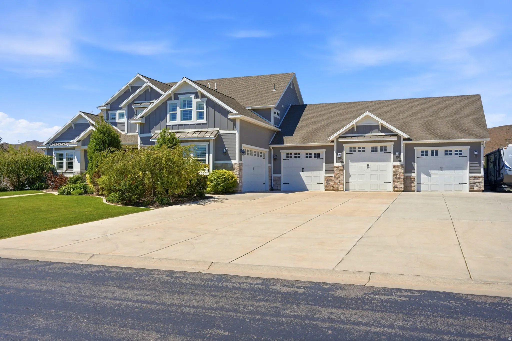 Contemporary residence featuring gray siding with white trim accents and stone detailing