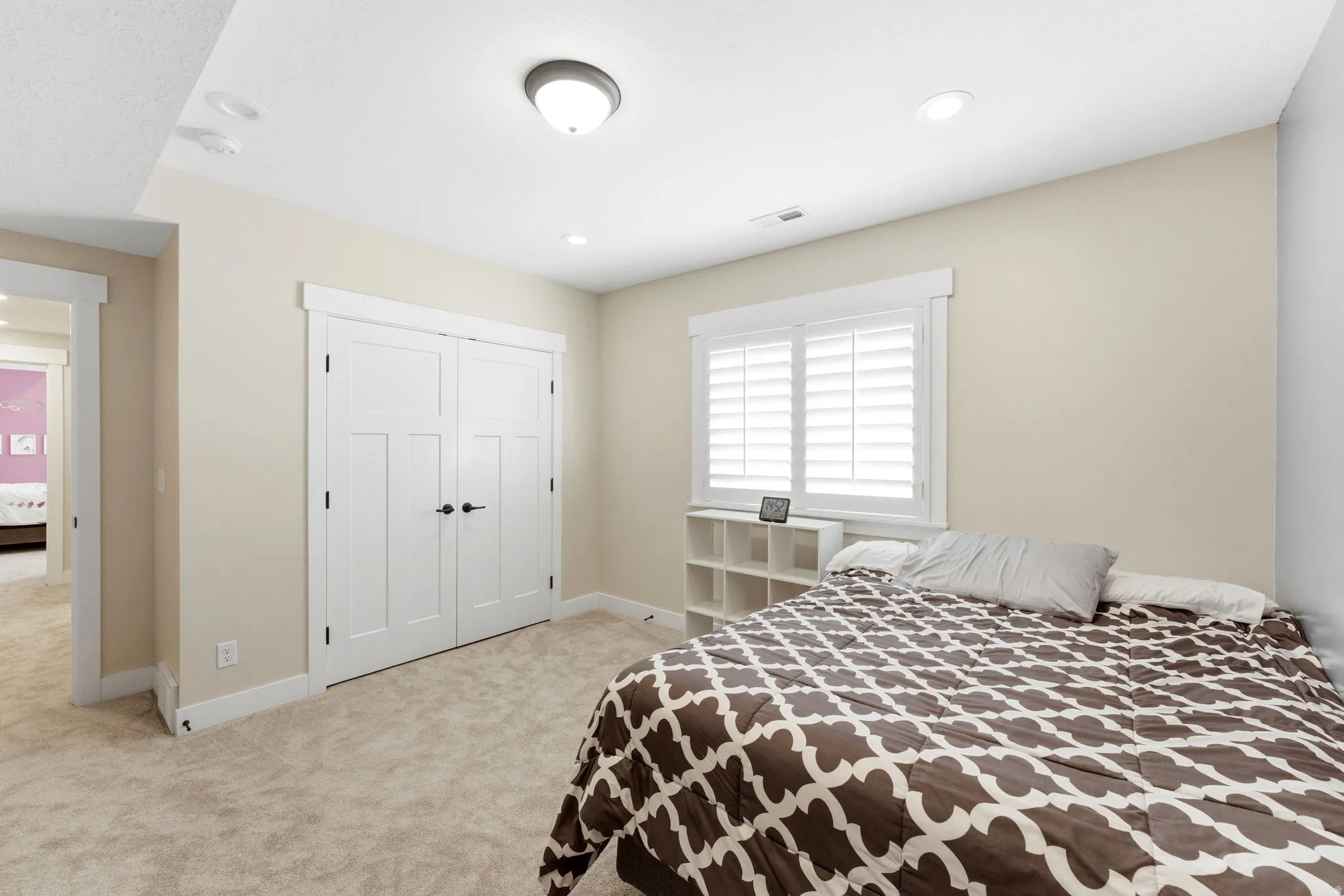 Bedroom featuring plush carpet flooring, recessed lighting, and a window with plantation shutters
