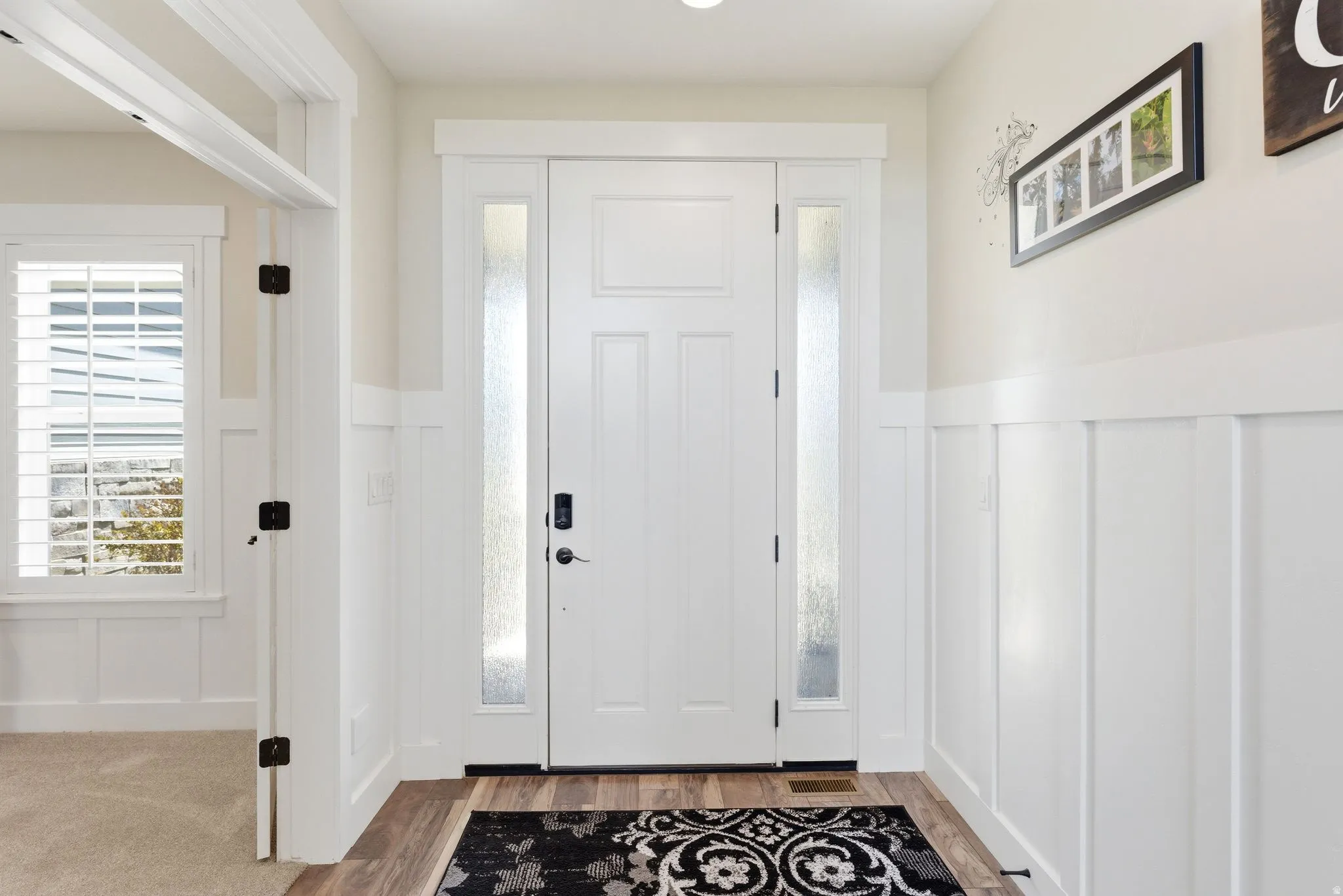 Entryway featuring a white paneled door with frosted glass sidelights and a smart lock