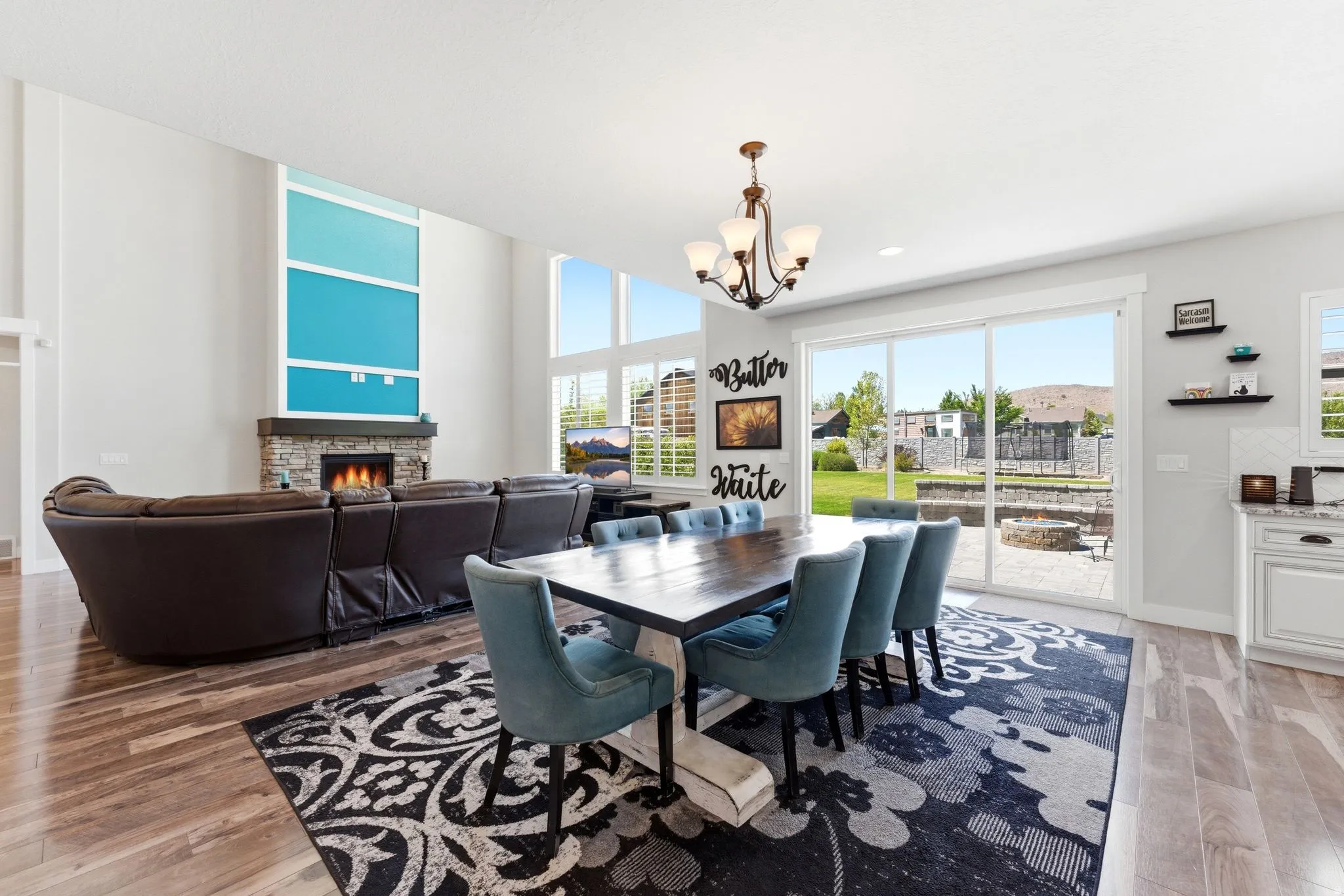 Spacious living area featuring high ceilings, wood-finish flooring, and a stone-faced fireplace
