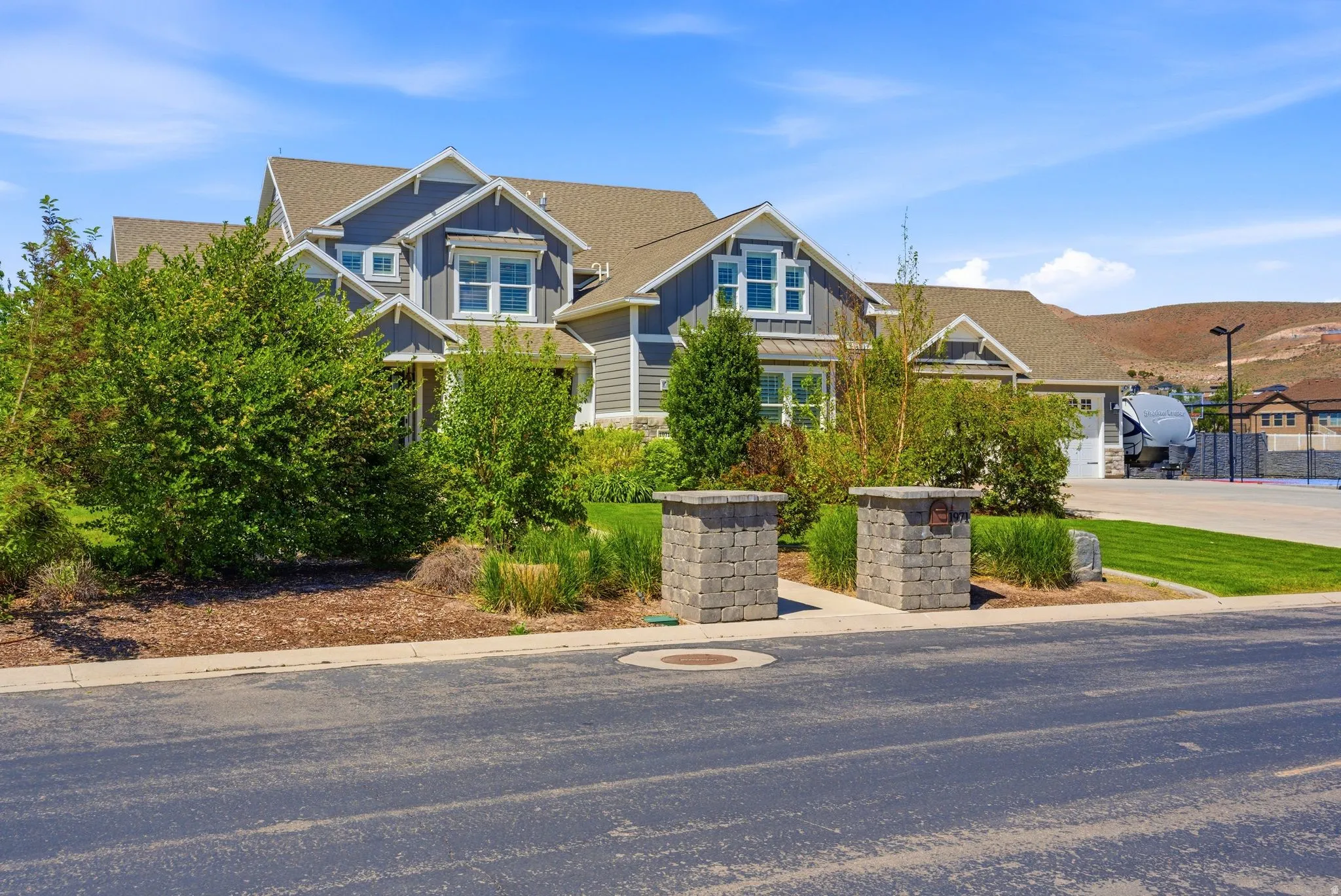 Modern Craftsman-style home featuring gabled rooflines, gray horizontal siding, white trim, and a two-car garage