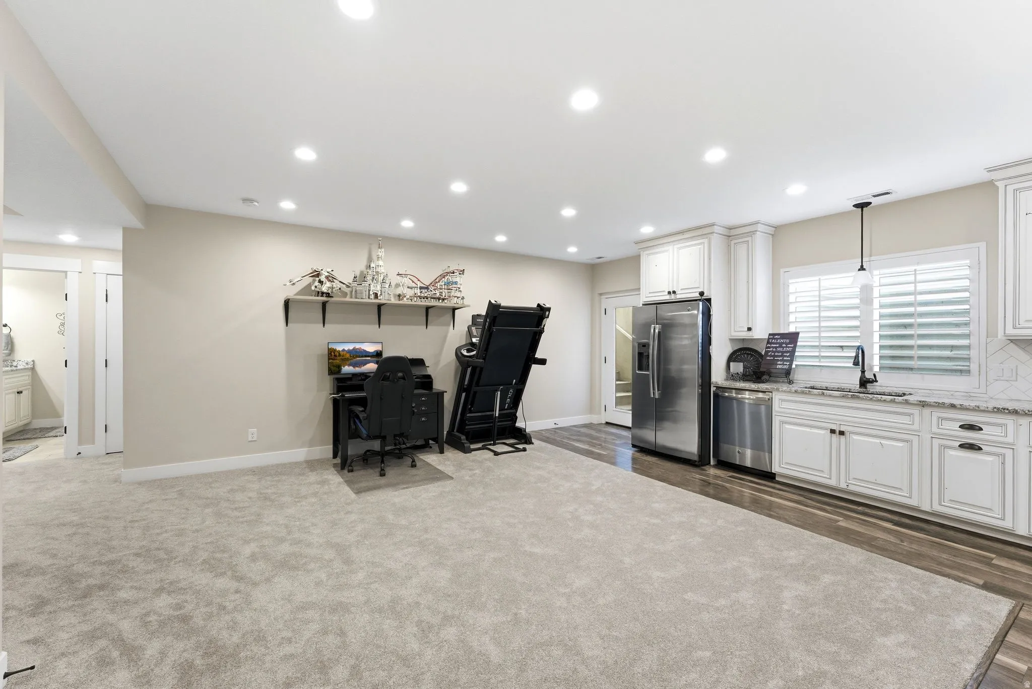Spacious open-concept area featuring recessed lighting, a fully equipped kitchen with stainless steel appliances, white cabinetry, and light-toned countertops
