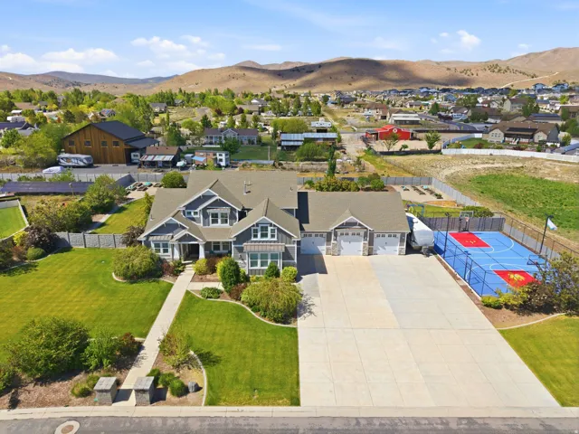 Spacious residence featuring a multi-car garage, expansive concrete driveway, and a dedicated sport court