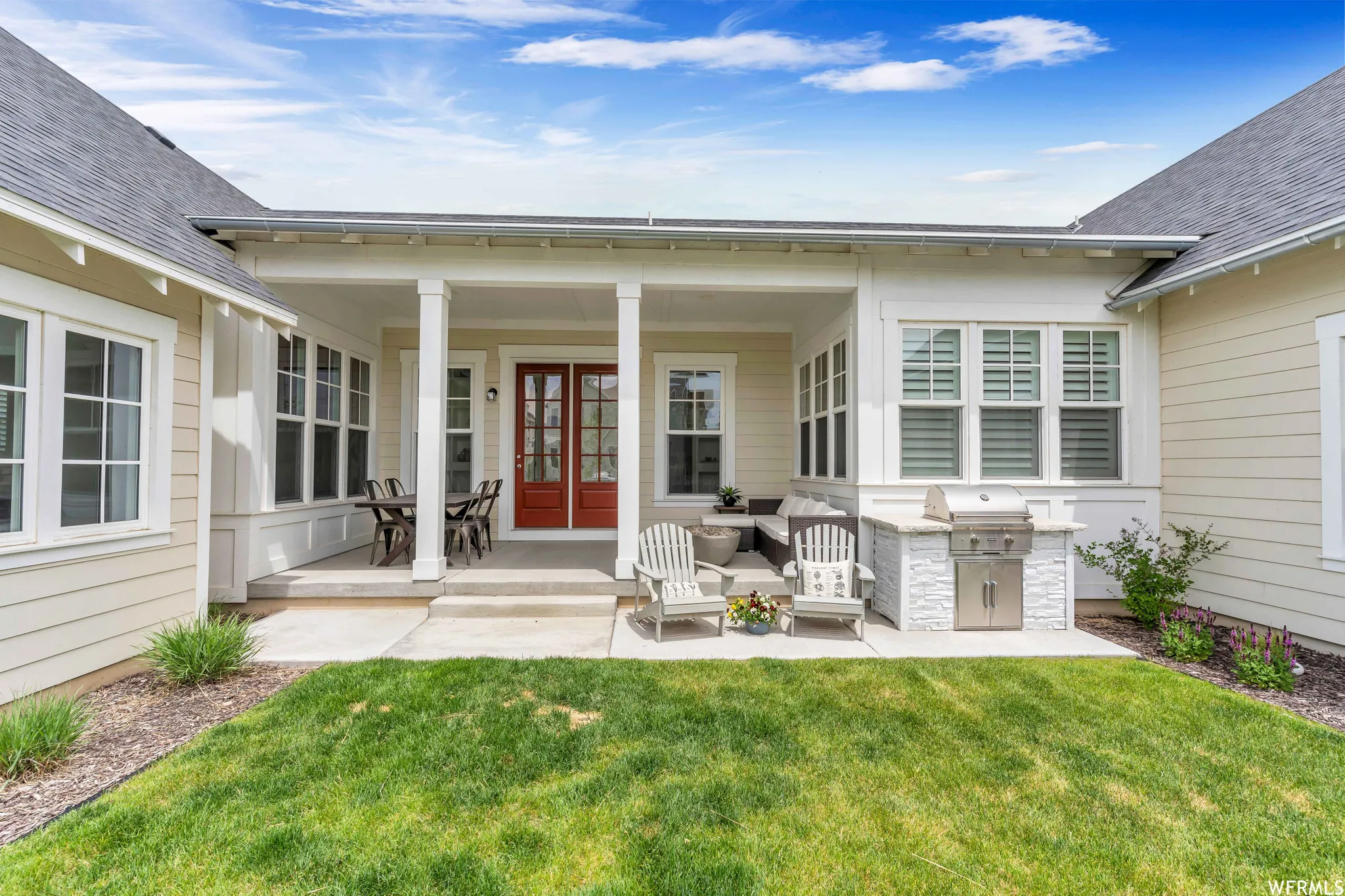 Covered patio featuring an outdoor kitchen with integrated grill, double French doors, large windows, and a concrete patio