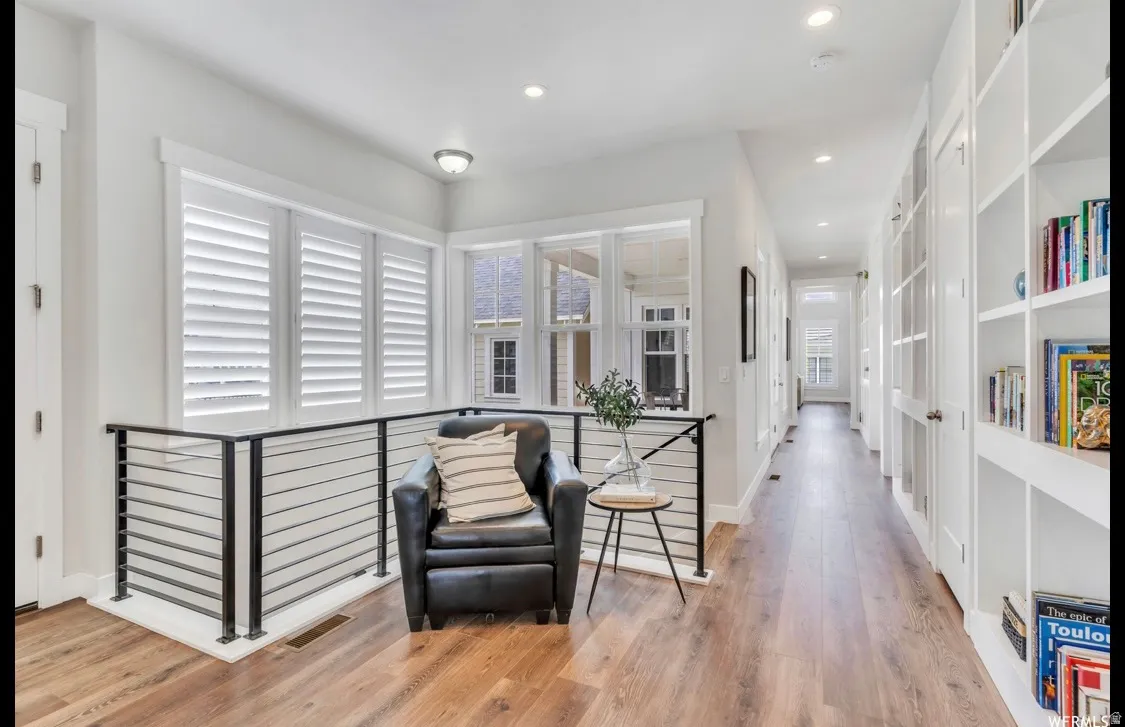 Hallway featuring wood-finish flooring, white walls, and recessed lighting