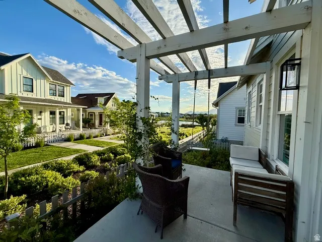 Exterior patio featuring a white pergola structure and concrete flooring