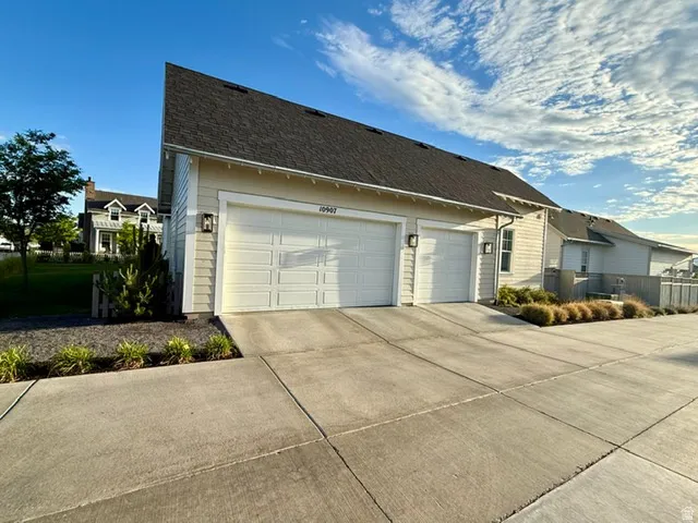 Two-car garage with panel doors, exterior wall lanterns, and a concrete driveway