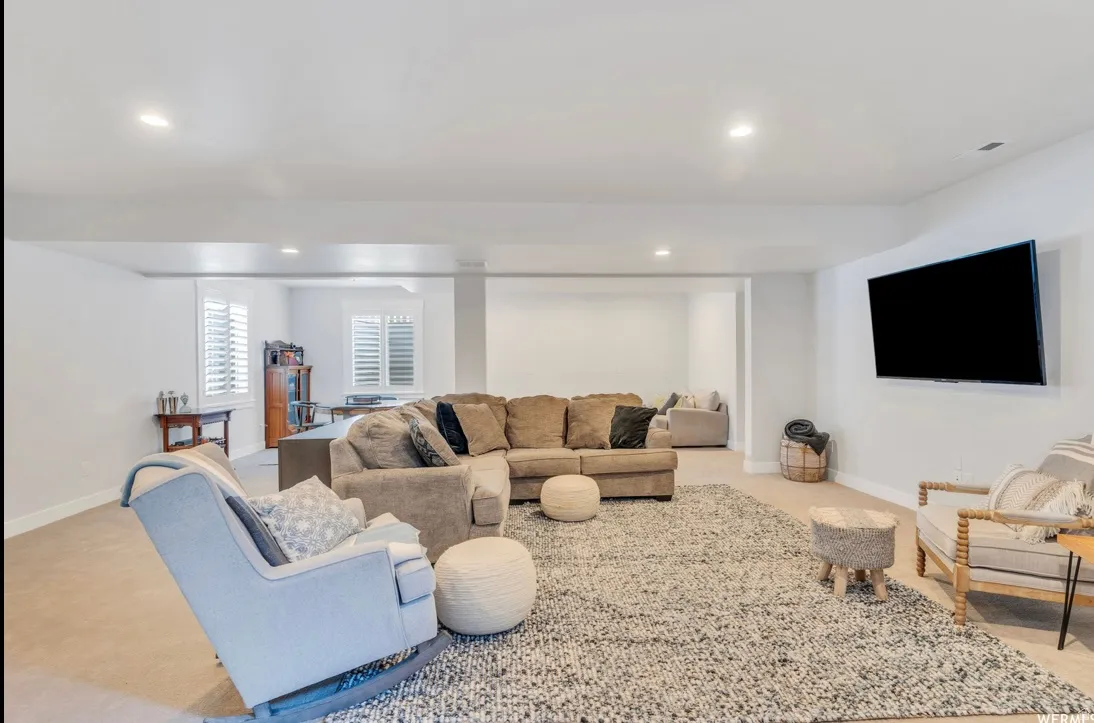 Spacious living area featuring recessed lighting, a mounted television, and plantation shutters