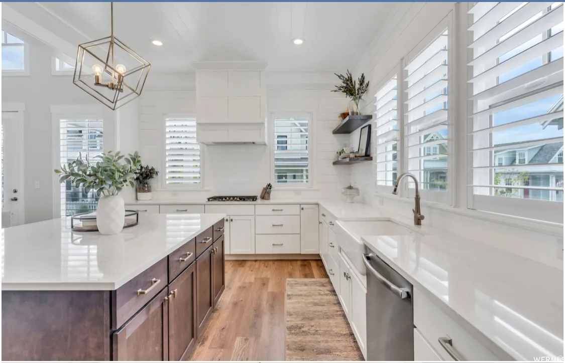 Spacious kitchen featuring a large island with dark wood-finish cabinetry, white countertops, and wood-finish flooring