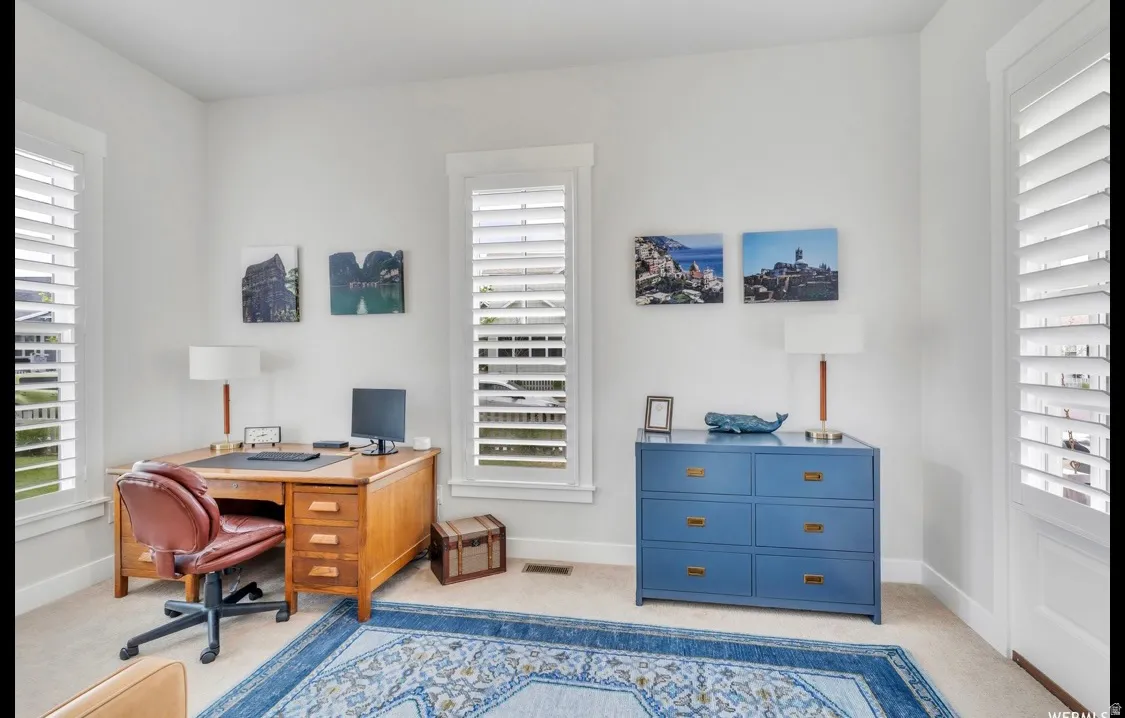 Bright room featuring two windows with white louvered shutters, light-toned carpeting, and white wall finishes